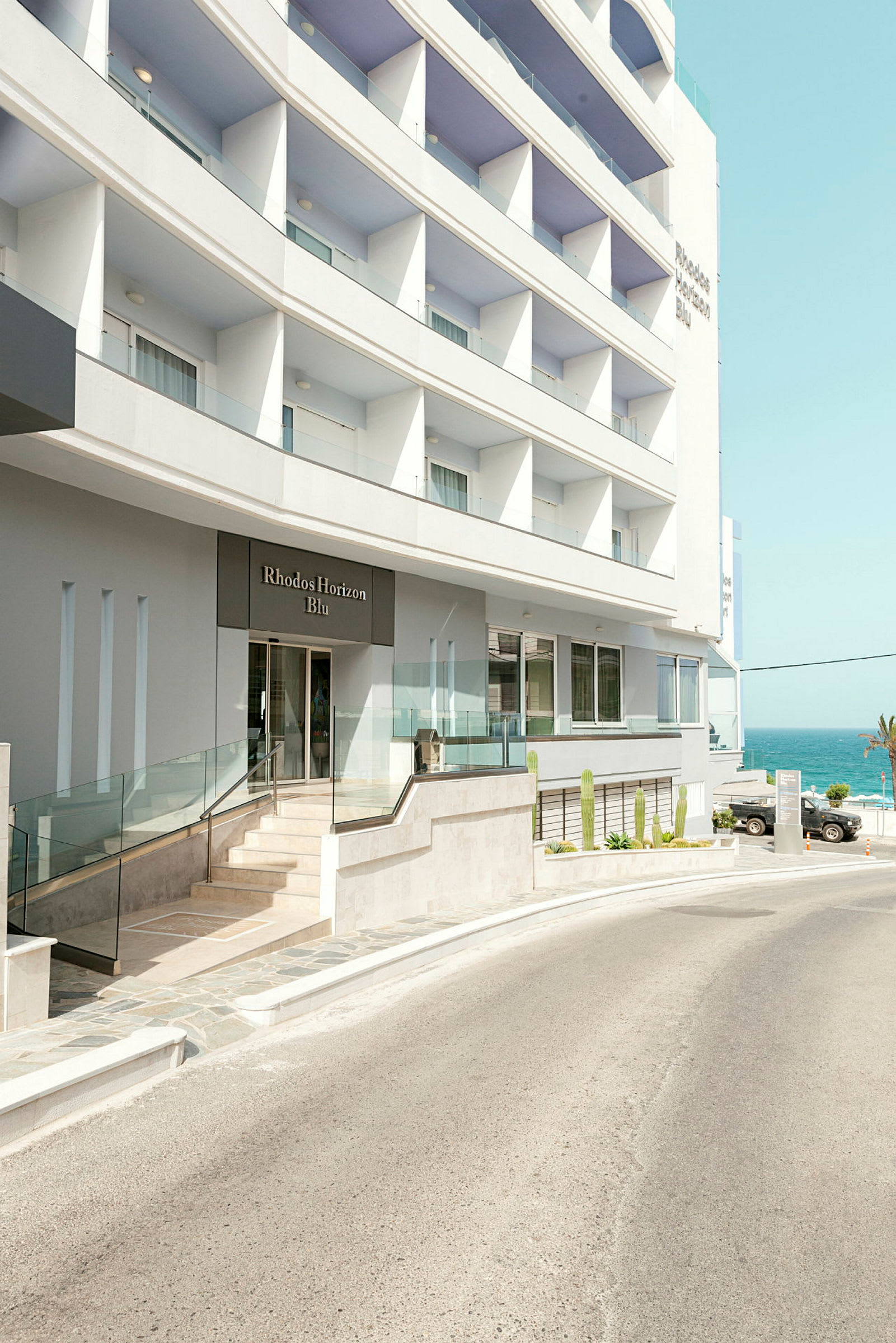 Hotelbygning med indgang og udsigt til havet. (AI-genereret tekst)