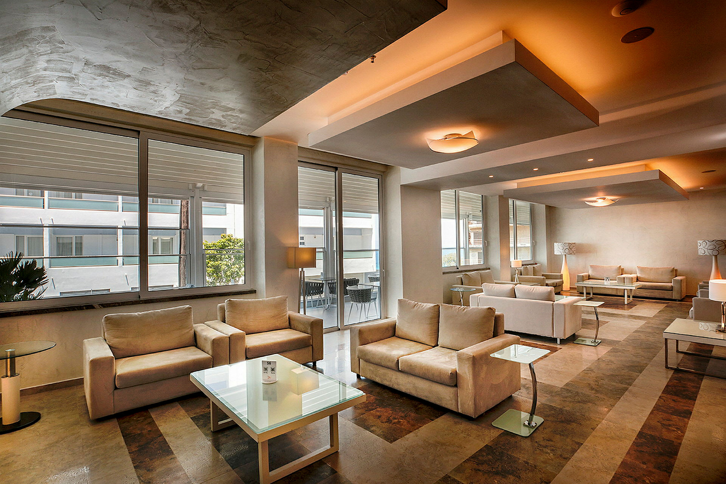 Moderne indrettet hotellobby med beige sofaer og glasborde. (AI-genereret tekst)