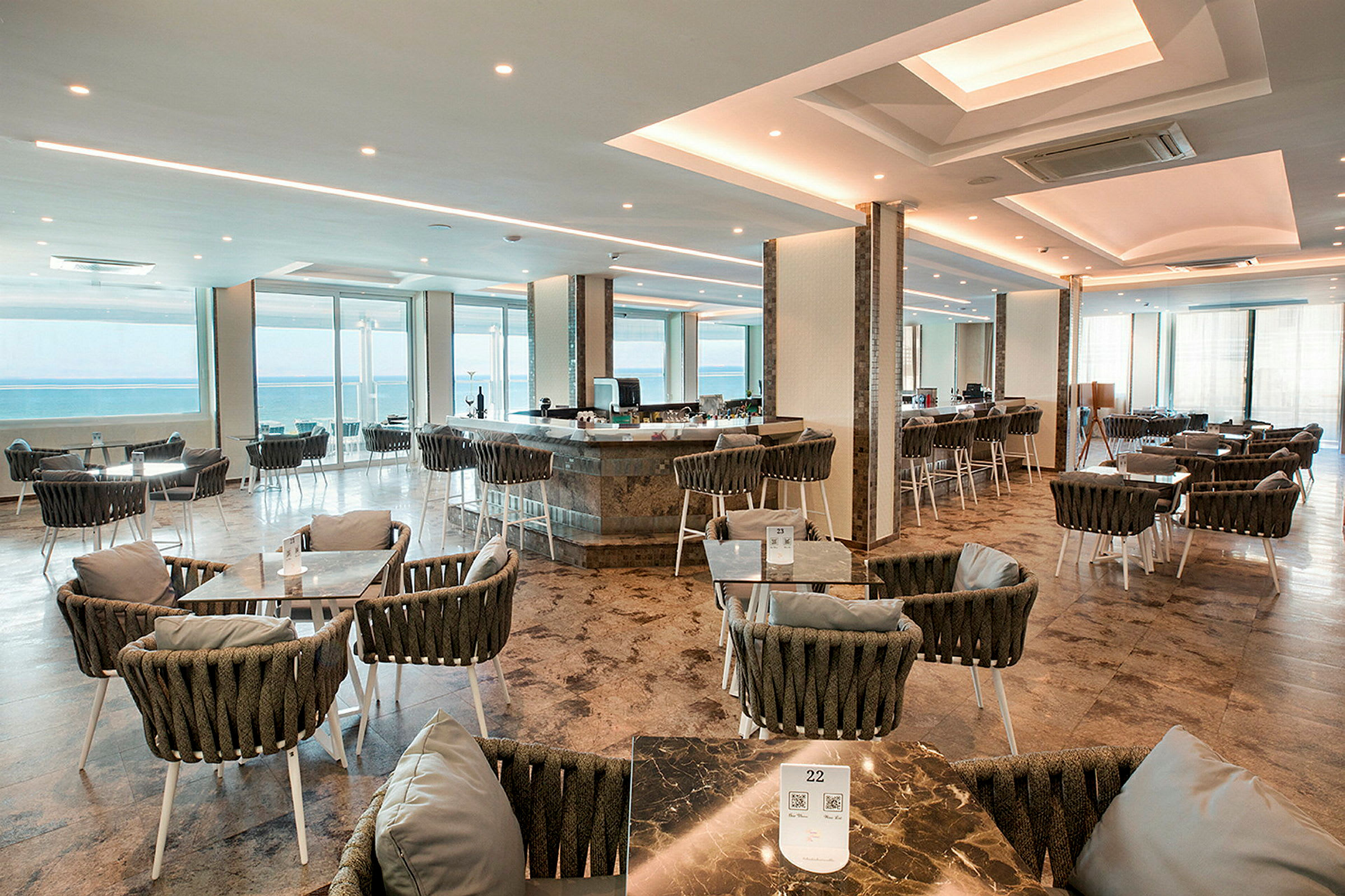 En rummelig restaurant med siddepladser og udsigt over havet. (AI-genereret tekst)