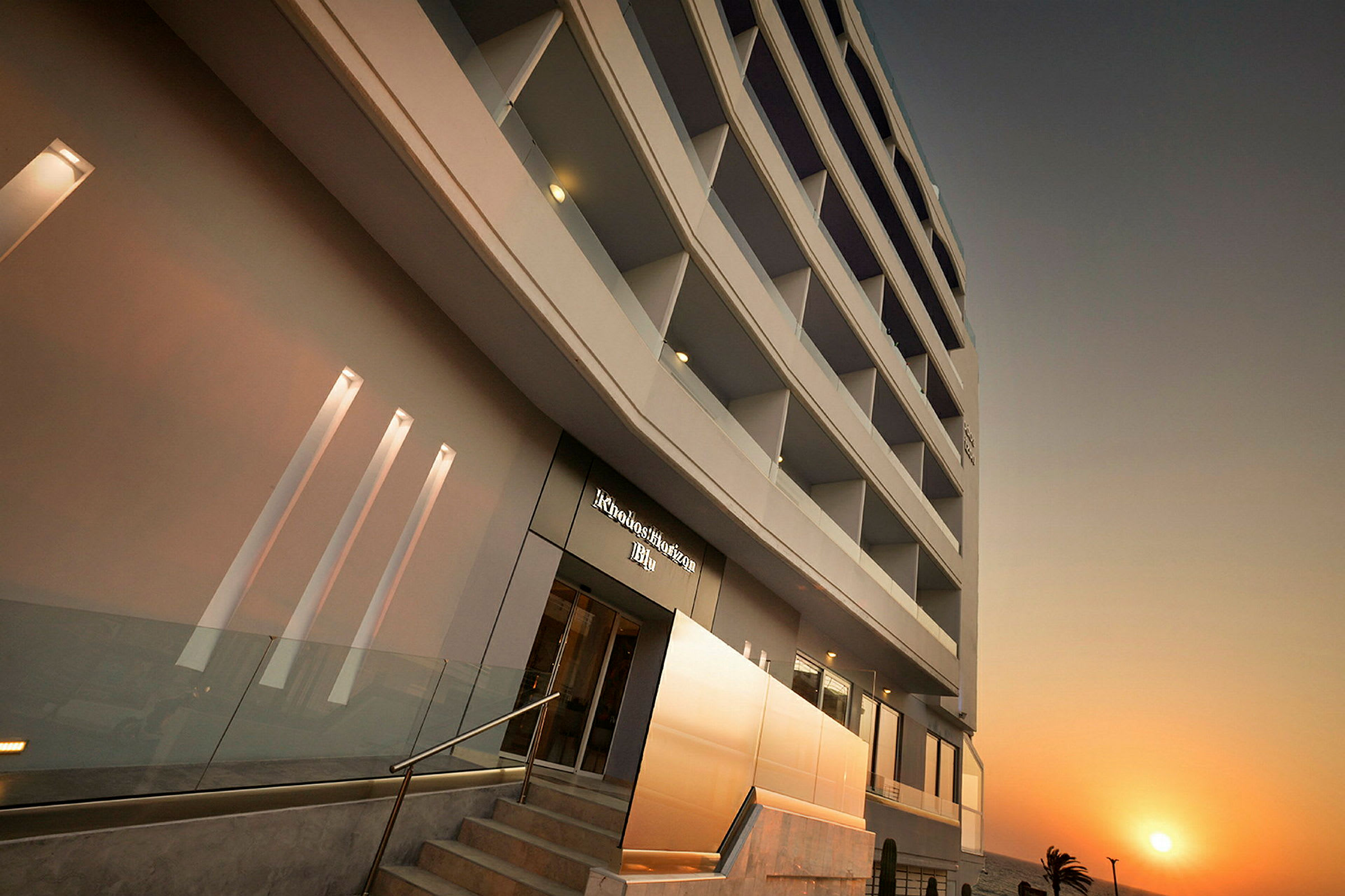 Moderne hotelbygning med flere etager mod en solnedgang. (AI-genereret tekst)