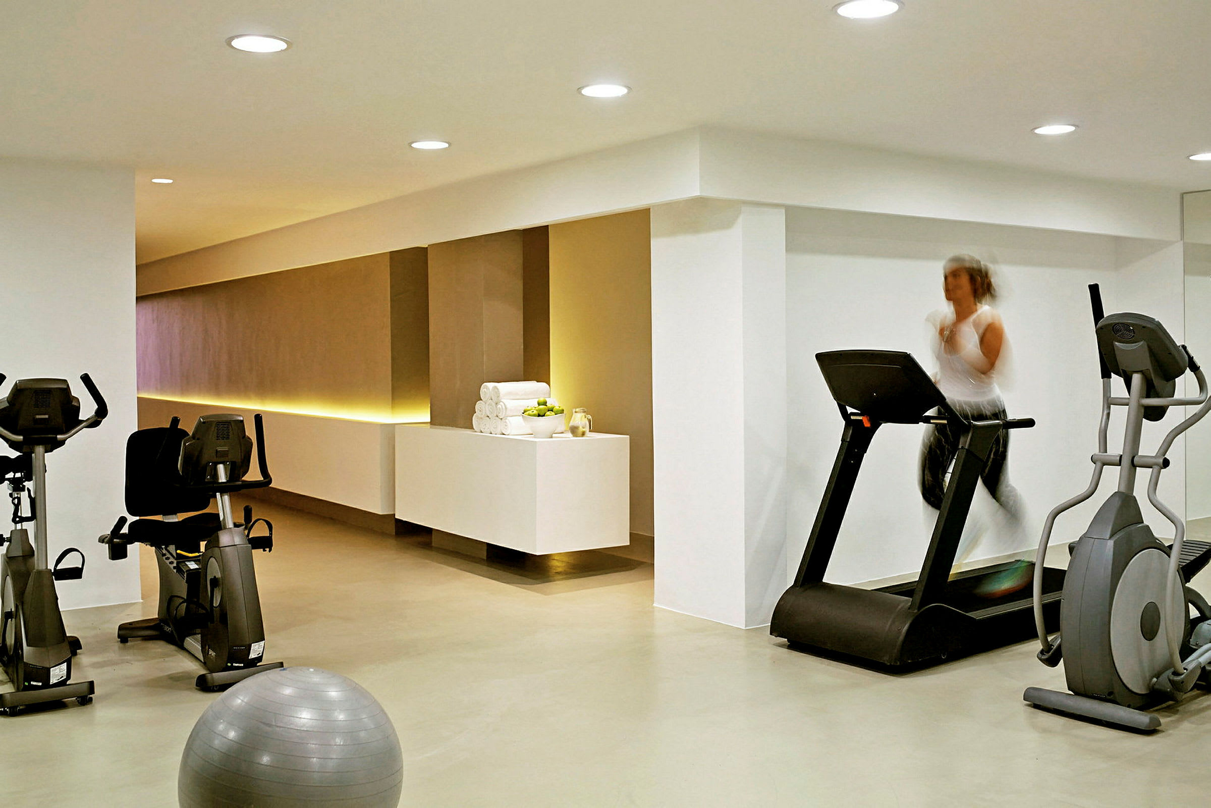 Et træningsrum med fitnessmaskiner og en pilatesbold. (AI-genereret tekst)