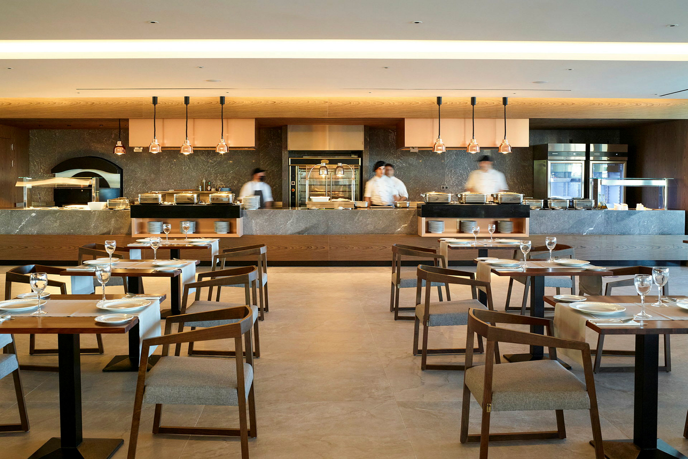 En moderne restaurant med dækkede borde, stole og et åbent køkkenområde. (AI-genereret tekst)