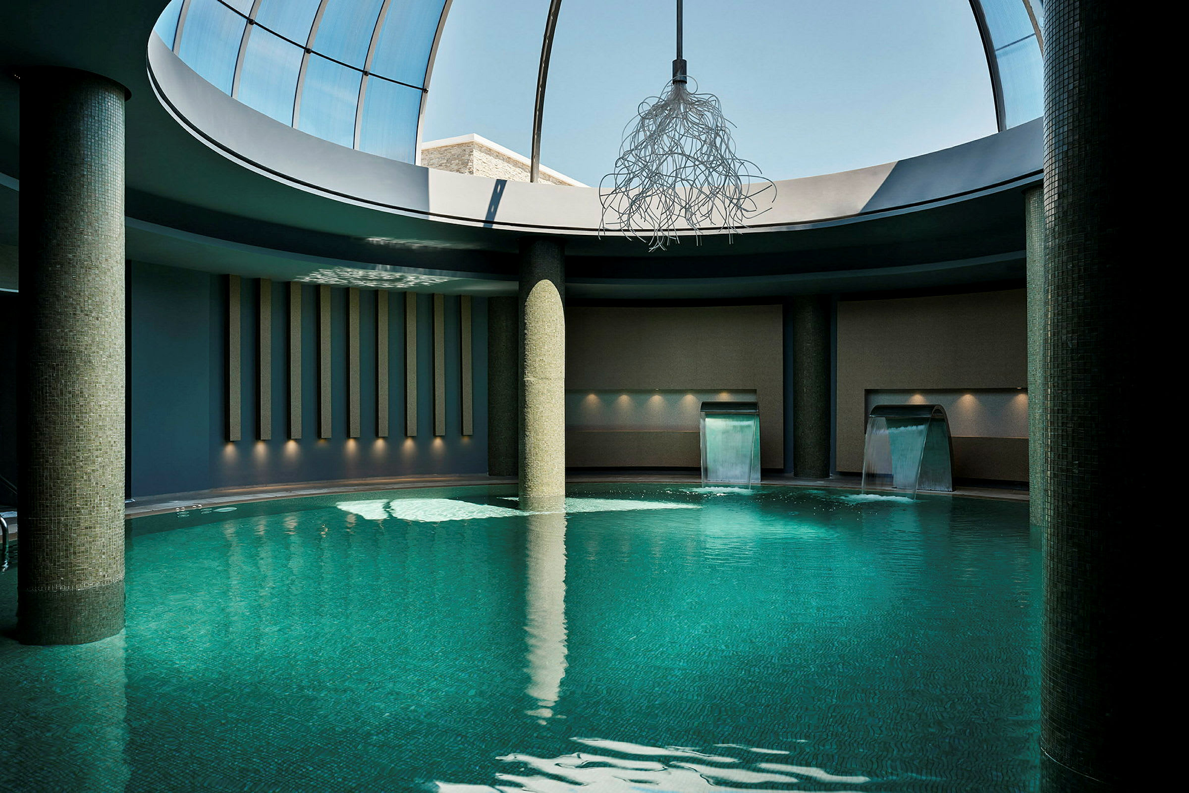 Indendørs pool med vandfald og moderne belysning. (AI-genereret tekst)