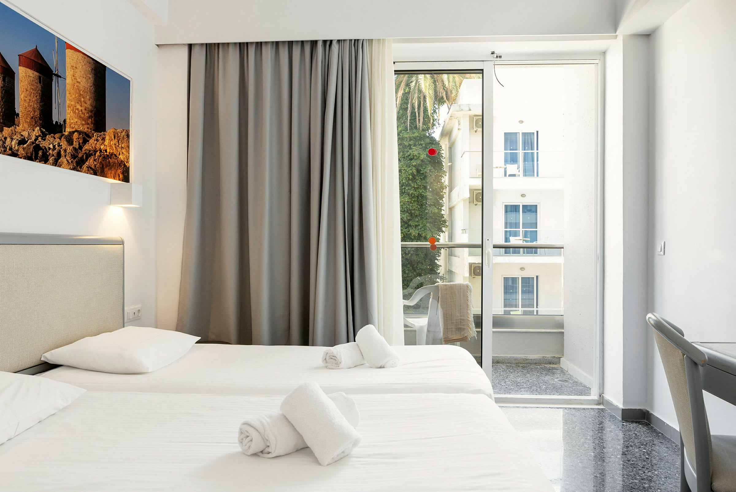Hotelværelse med to enkeltsenge og balkon med udsigt. (AI-genereret tekst)