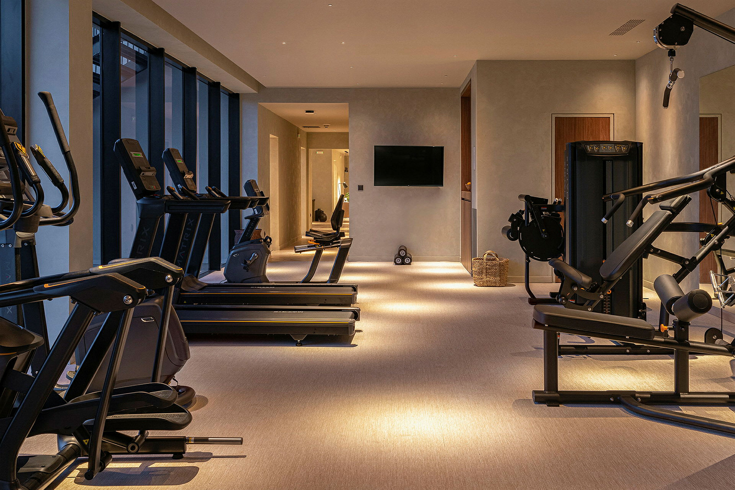 Et moderne fitnesscenter med træningsmaskiner og store vinduer. (AI-genereret tekst)