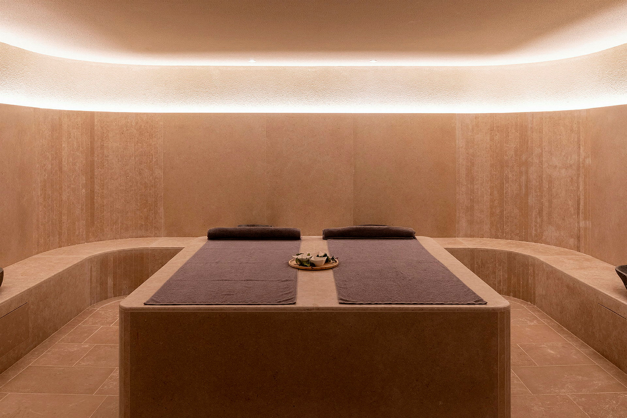 Et moderne spa-rum med afslappende belysning og to massageborde med håndklæder. (AI-genereret tekst)