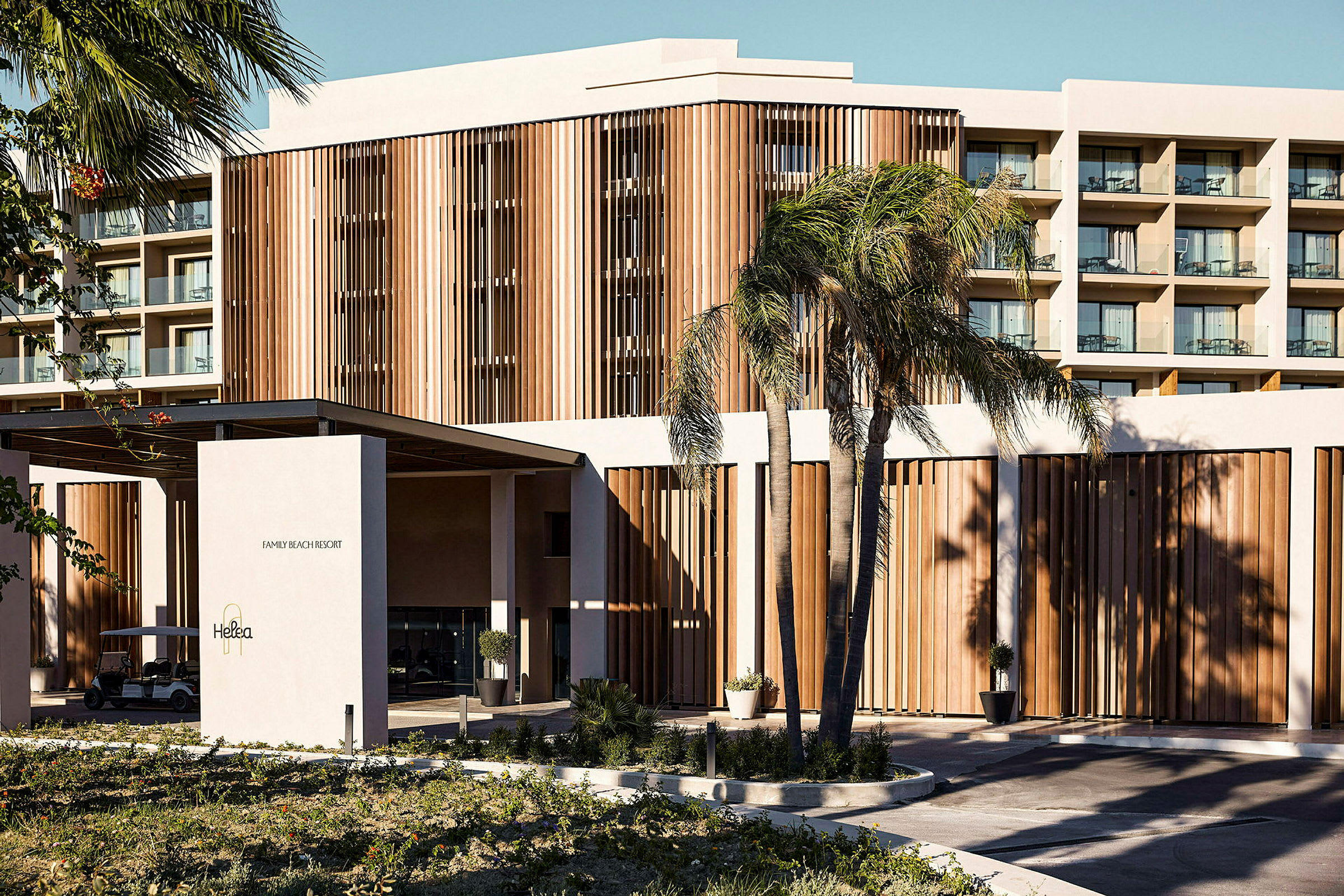 Et hotel med moderne arkitektur og træpaneler omgivet af palmer. (AI-genereret tekst)