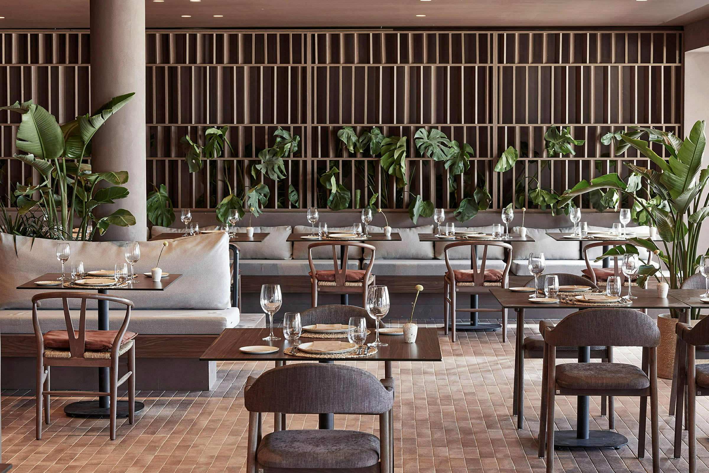 Restaurant med dækkede borde, moderne møbler og grønne planter. (AI-genereret tekst)