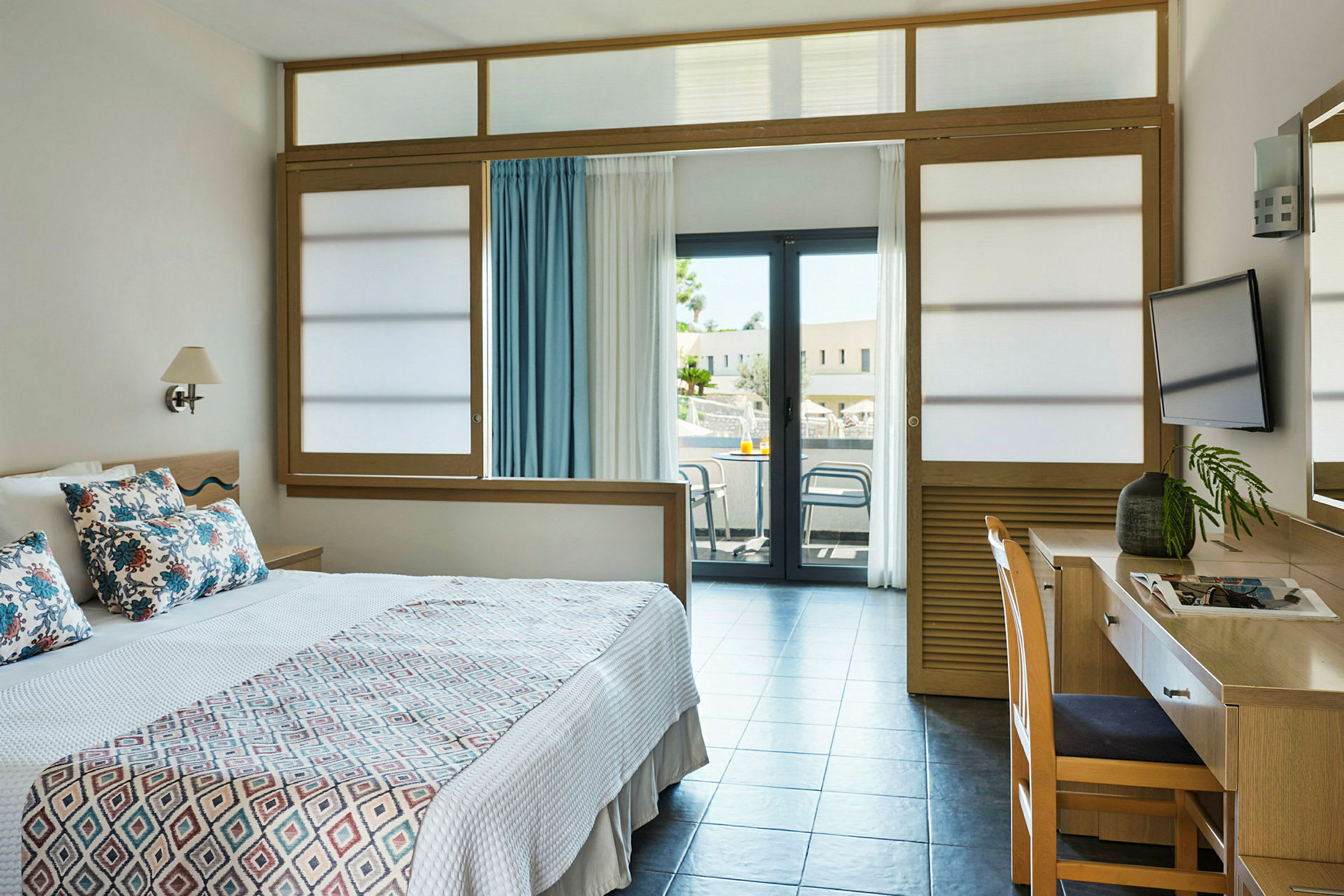 Hotelværelse med en seng, skrivebord og balkon. (AI-genereret tekst)