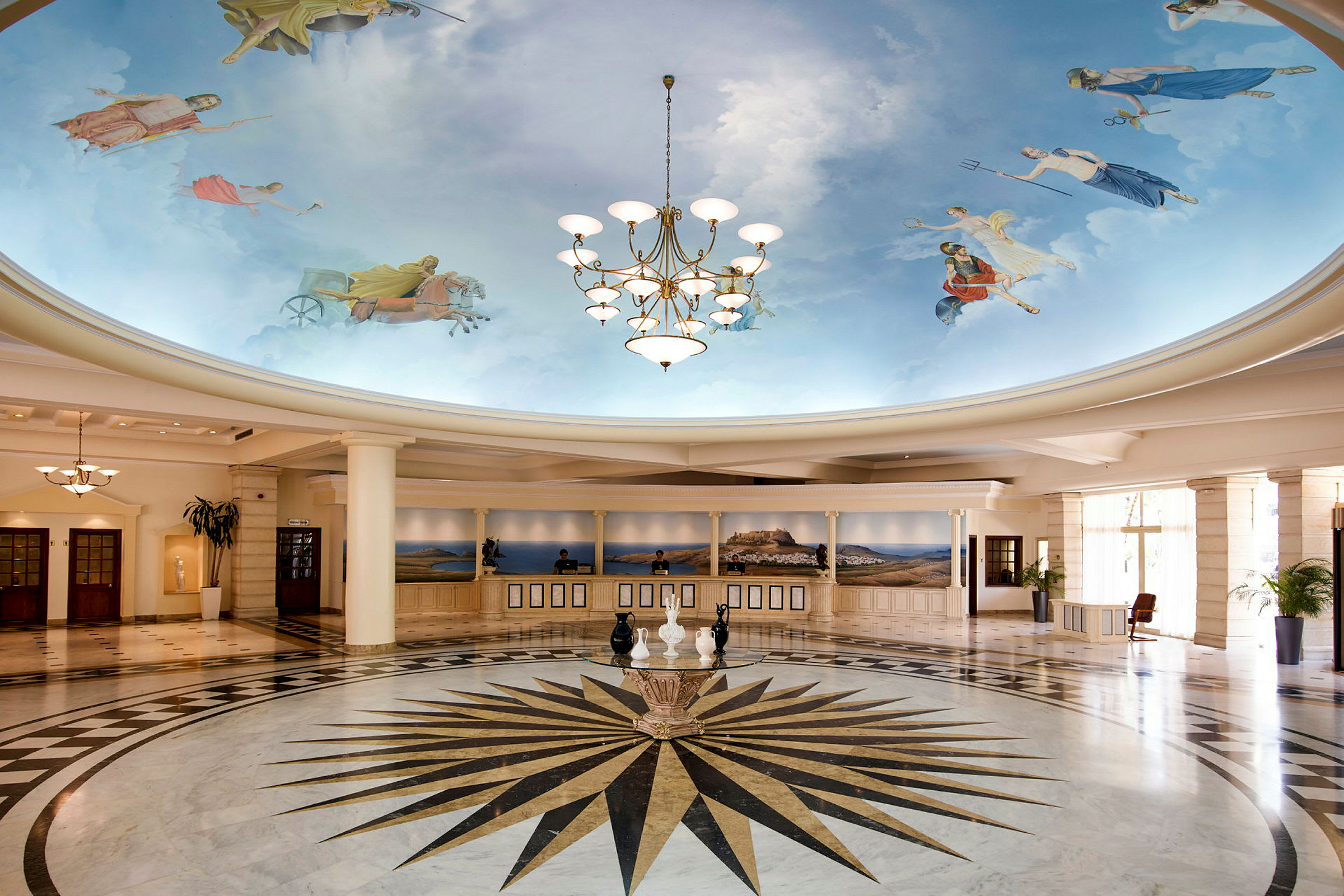 En hotellobby med malede himmelmotiv på loftet og en lysekrone. Der er en reception længere bagved. (AI-genereret tekst)