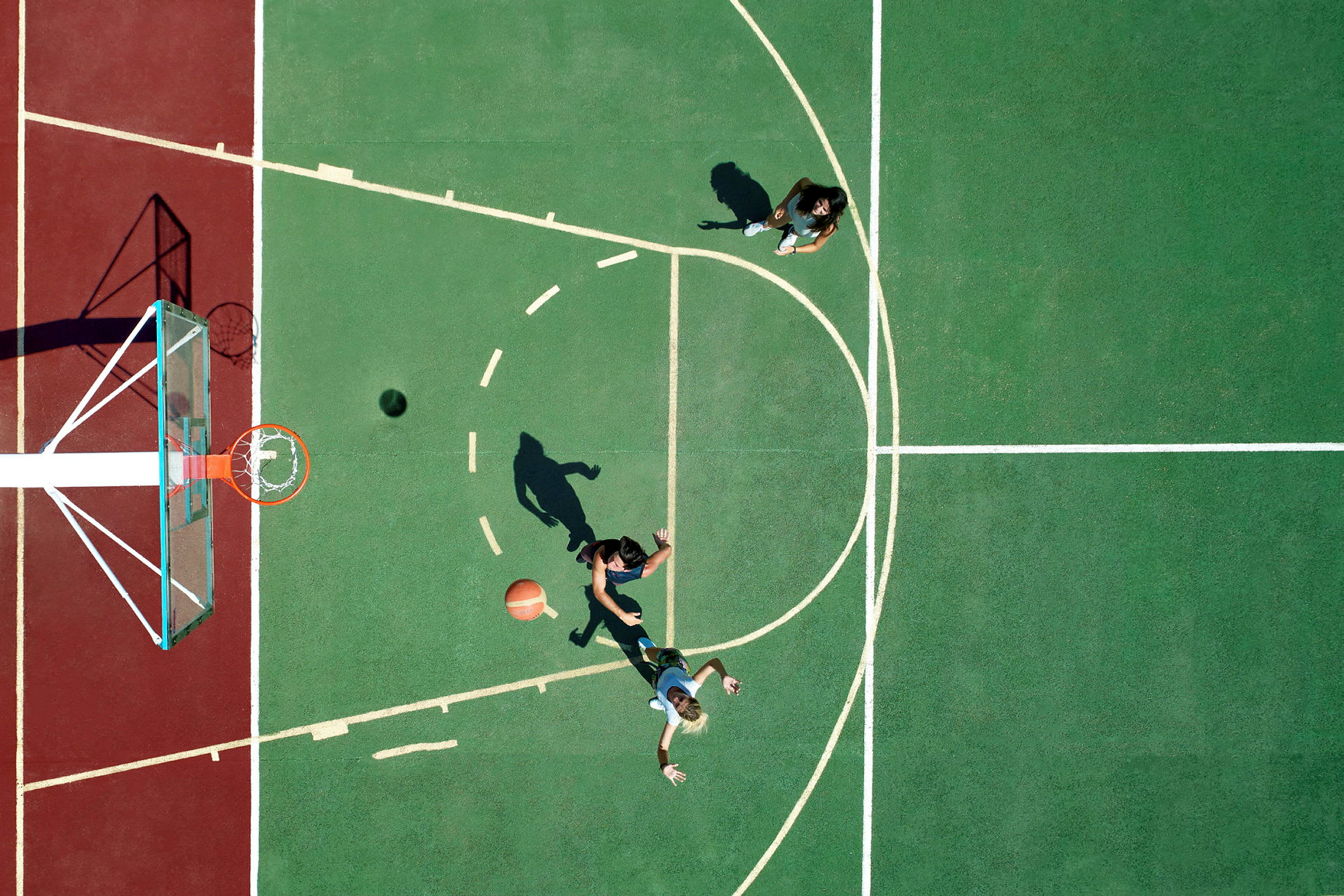 To personer spiller basketball på en udendørs bane set ovenfra. (AI-genereret tekst)