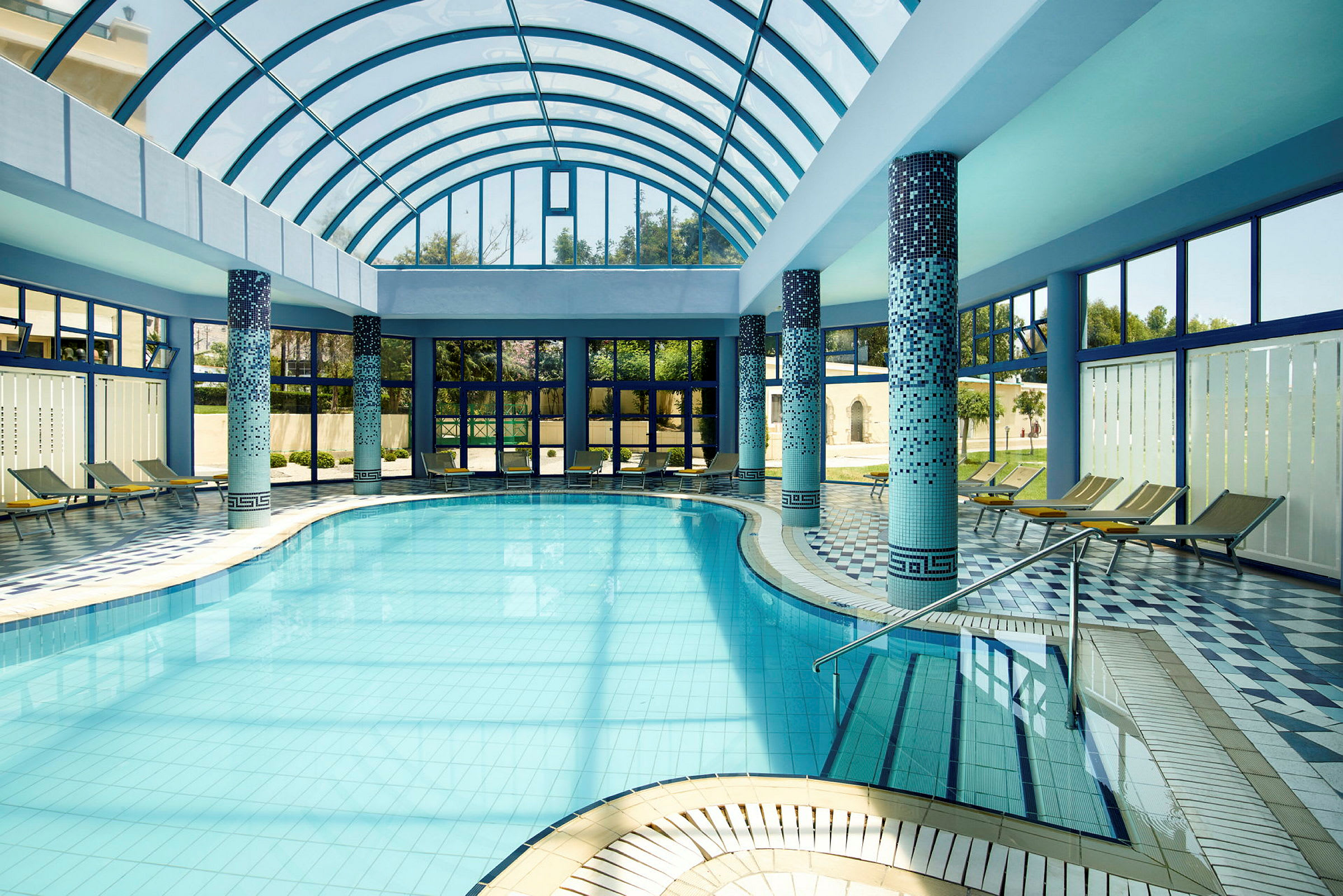 En indendørs pool med glastag og solsenge omkring. (AI-genereret tekst)