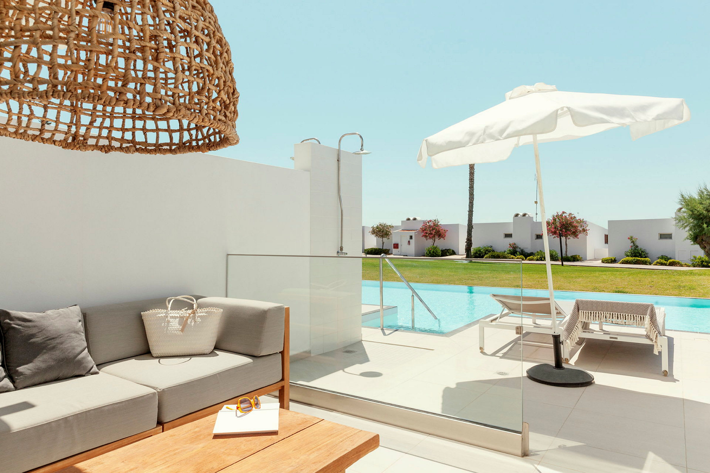Udendørsmiljø med sofa, parasol og pool. (AI-genereret tekst)