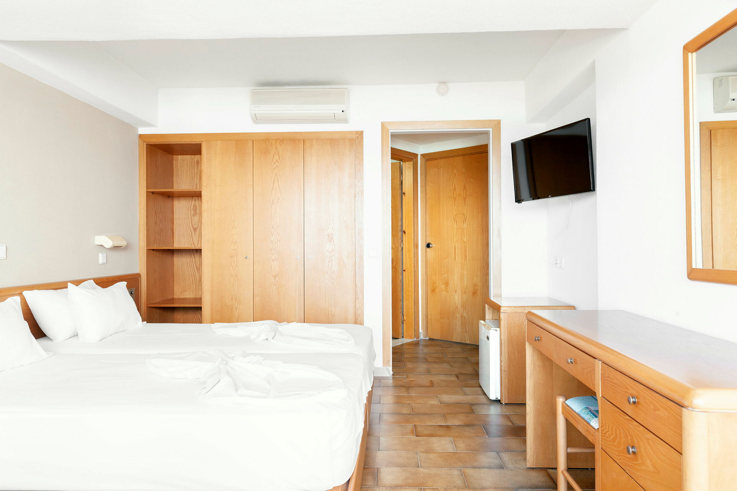 Hotelværelse med to enkeltsenge, garderobe, skrivebord og spejl. (AI-genereret tekst)