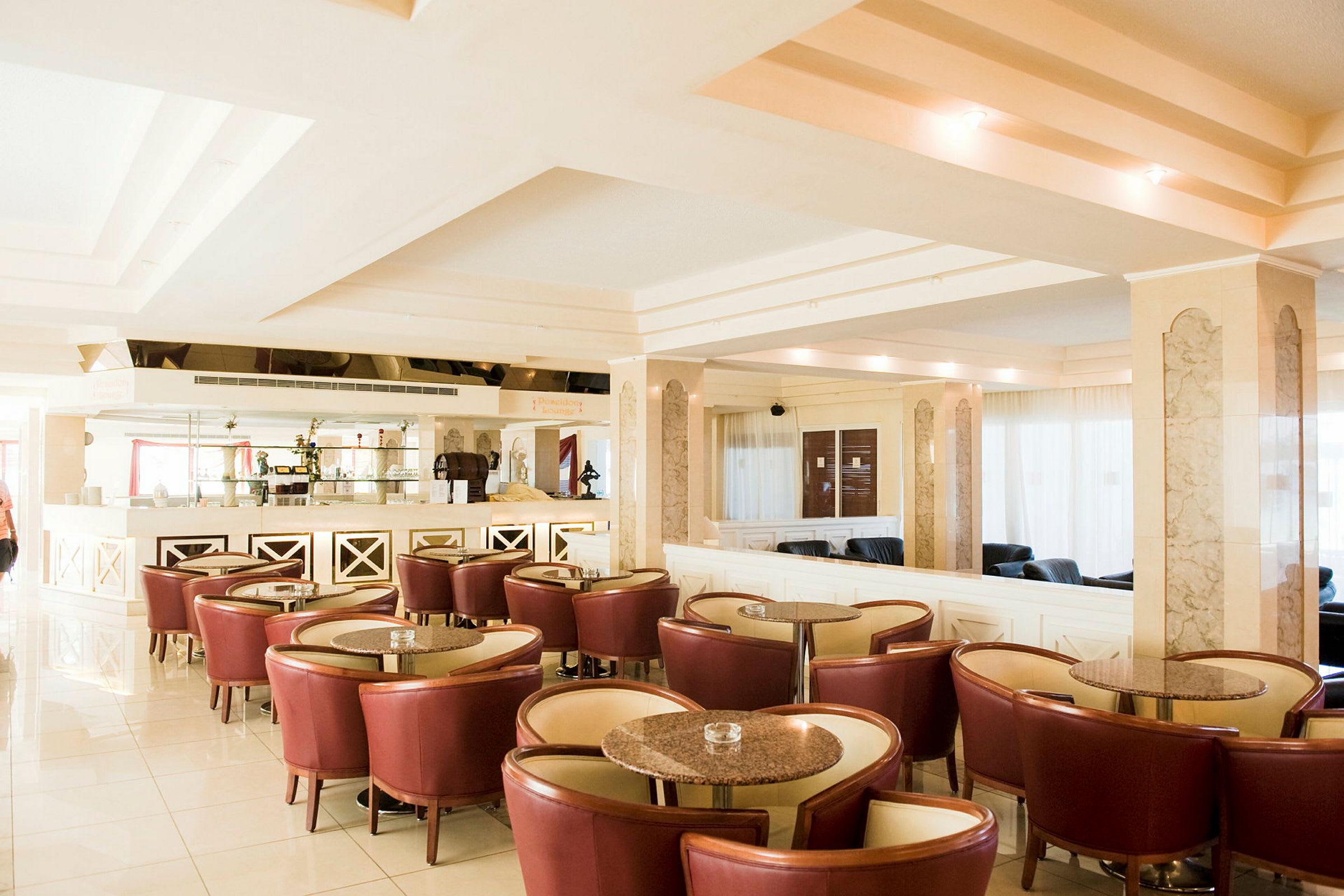 Billede af en moderne hotellounge med røde stole, runde borde og en lyseffektiv indretning. (AI-genereret tekst)