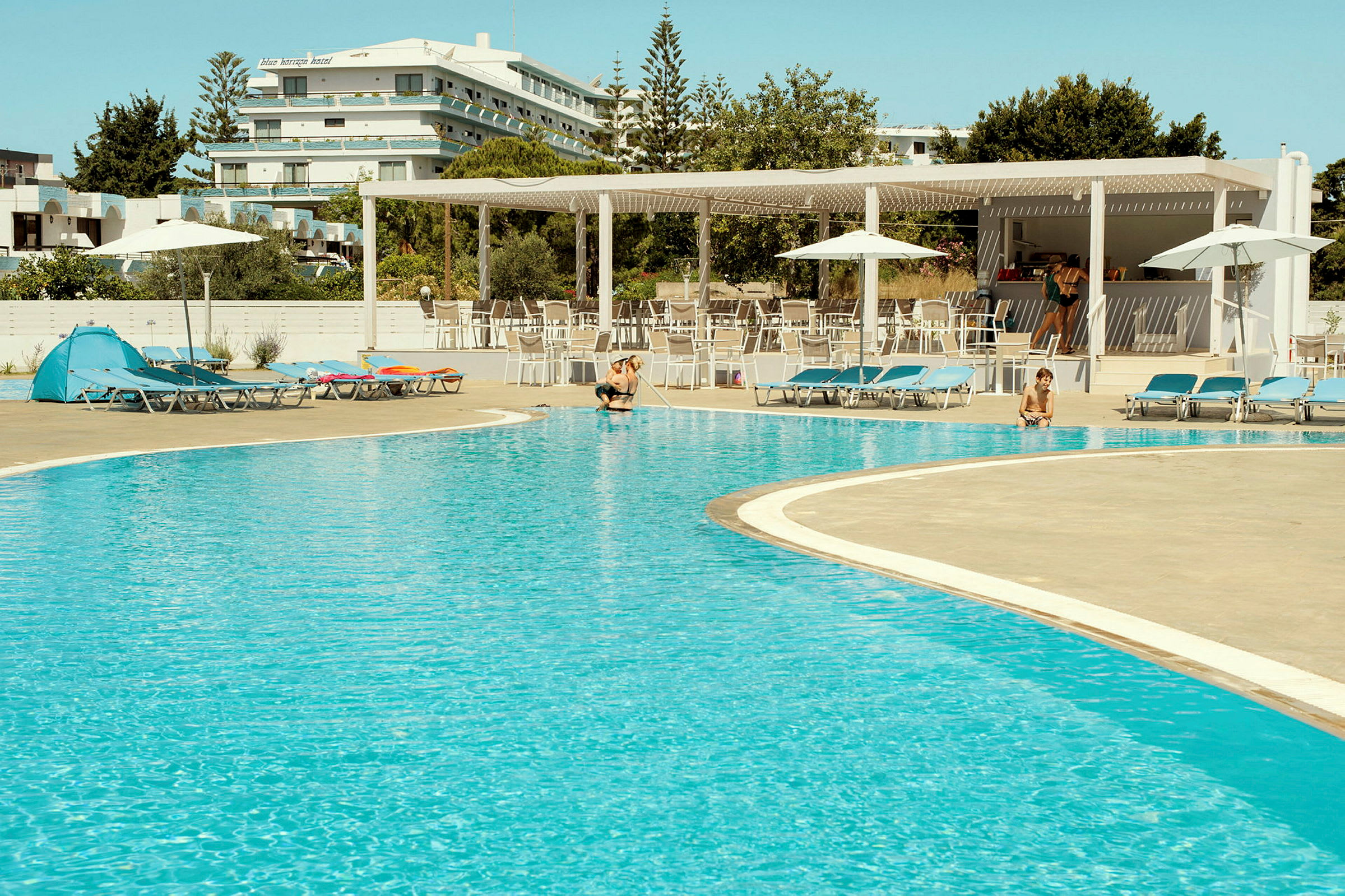 En udendørs pool ved et hotel, omgivet af liggestole og parasoller. (AI-genereret tekst)