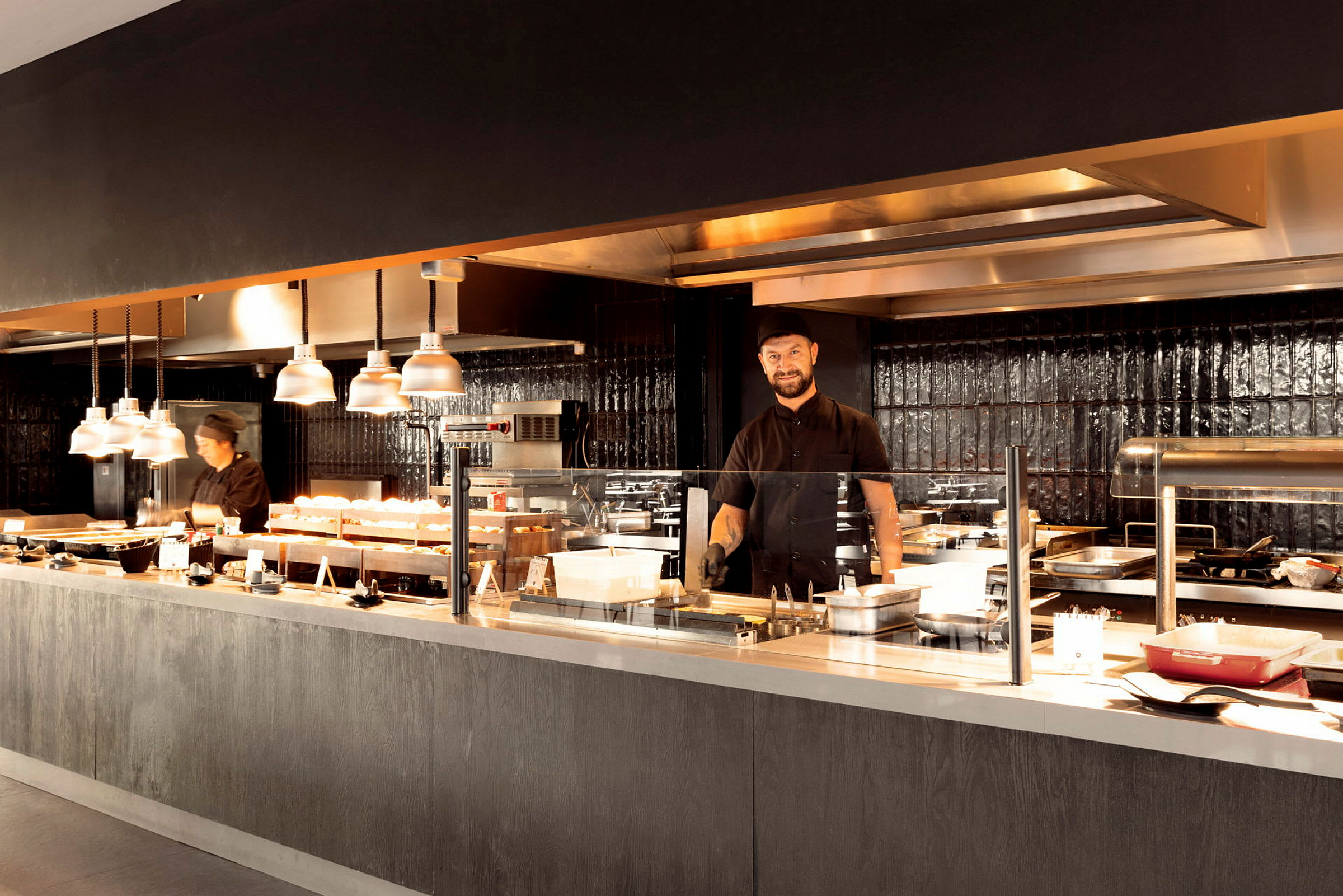 Et restaurantkøkken med flere madstationer og belysning. (AI-genereret tekst)