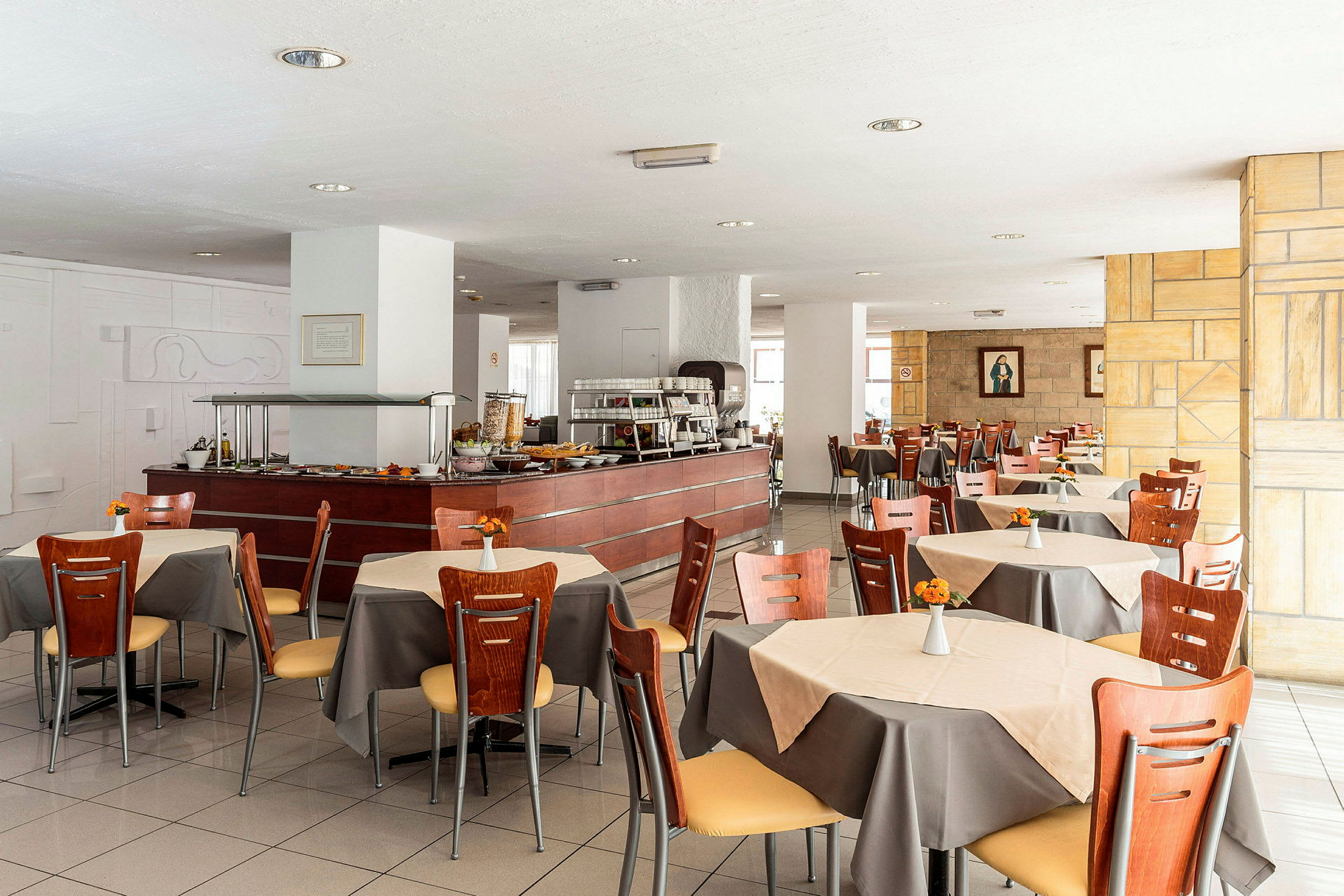 Restauranten spisesal med borde, stole og en buffetdisk. (AI-genereret tekst)