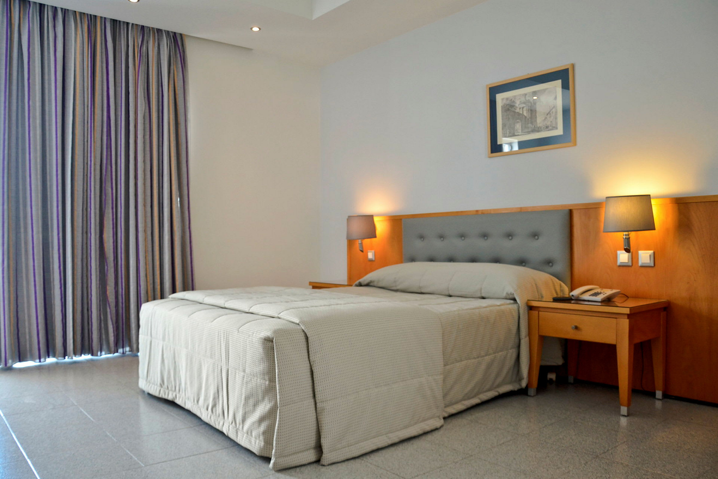 Hotelværelse med en seng og to sengelamper. (AI-genereret tekst)