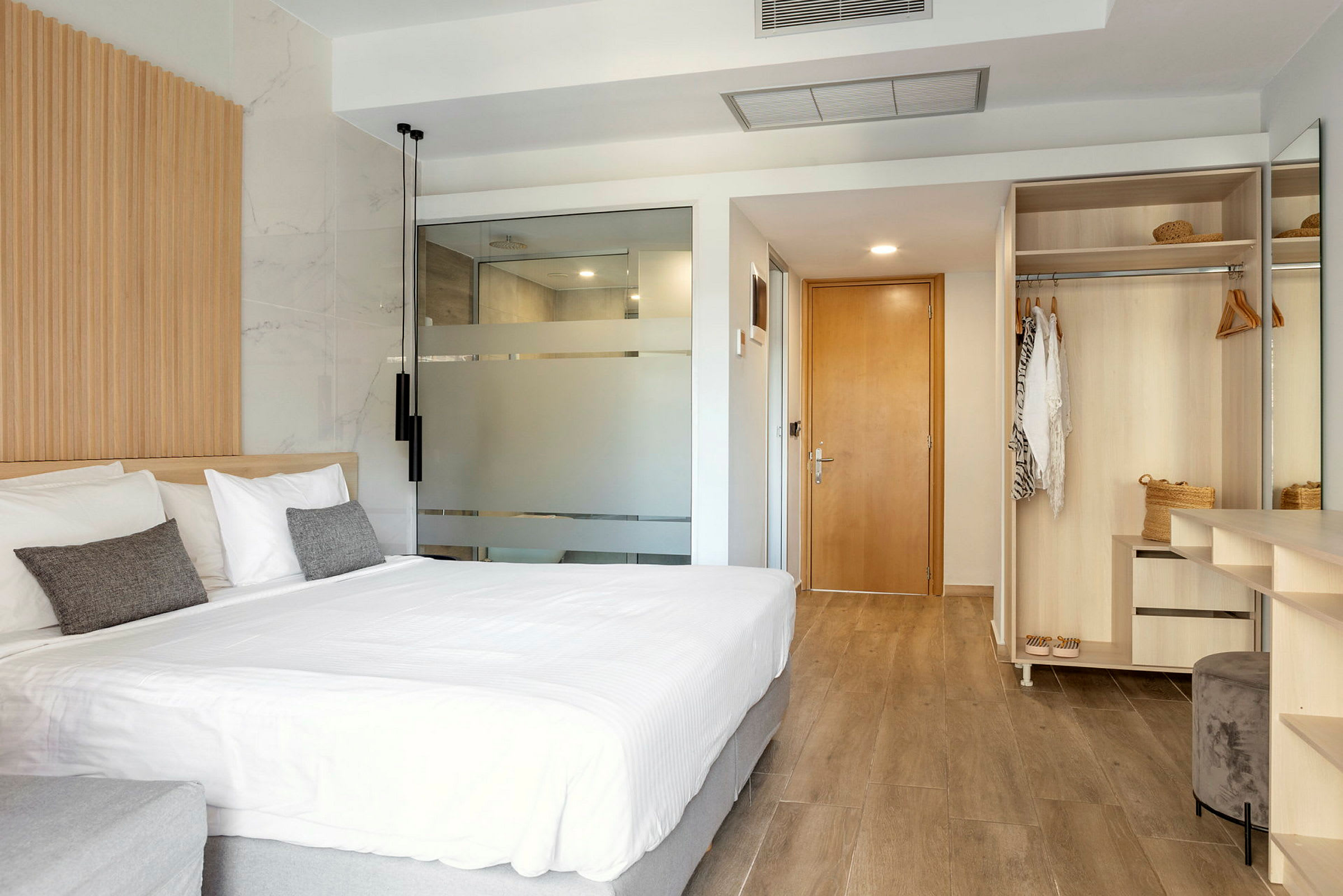 Et moderne hotelværelse med stor seng, garderobe og badeværelsesdør. (AI-genereret tekst)