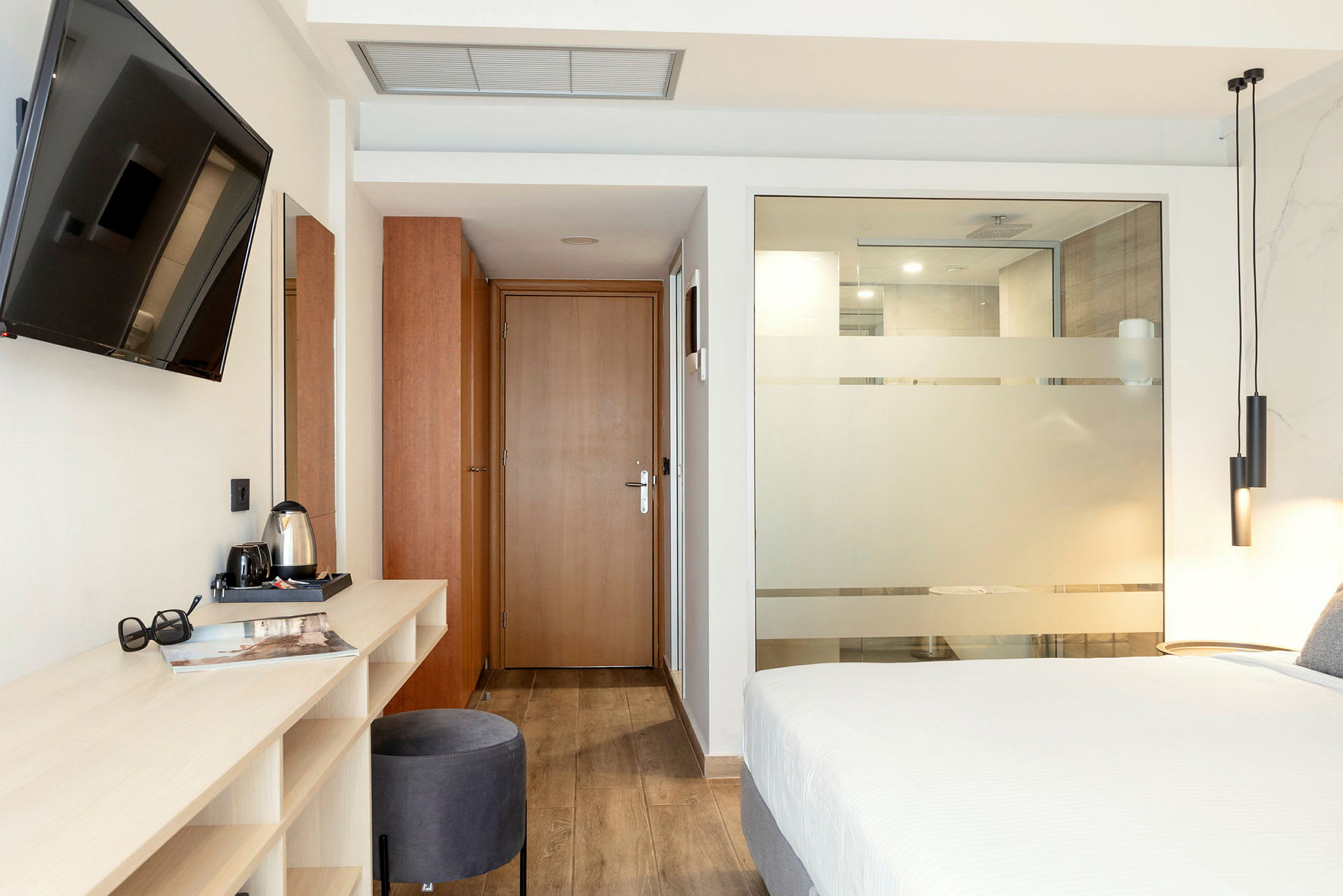 Moderne hotelværelse med seng, skrivebord og tv. (AI-genereret tekst)