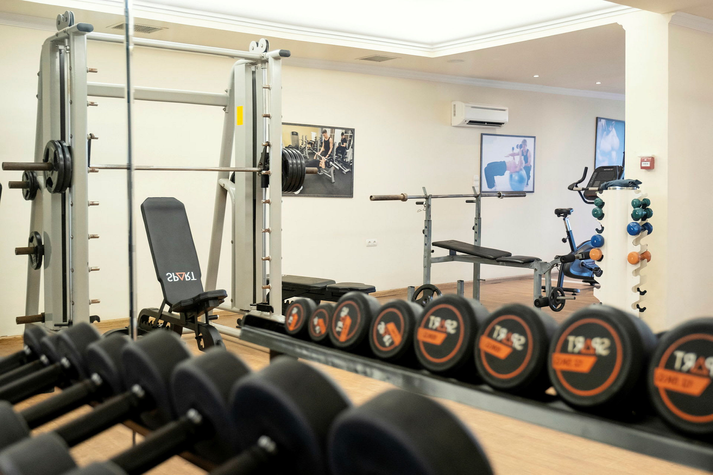 Et fitnesscenter med træningsmaskiner, bænkpres og håndvægte. (AI-genereret tekst)