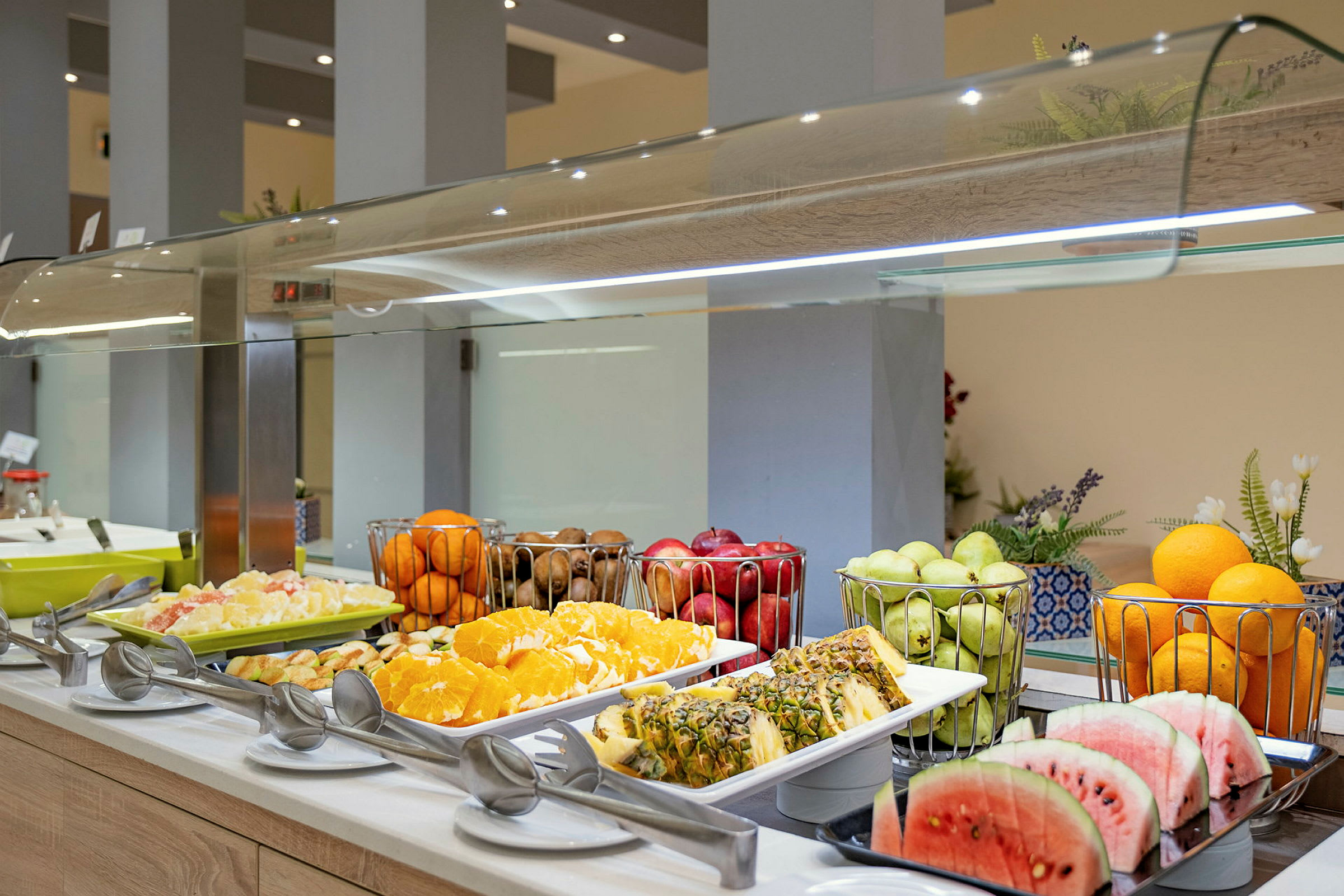 En buffet med forskellige frugter, herunder skåret vandmelon og ananas, appelsiner og druer. (AI-genereret tekst)