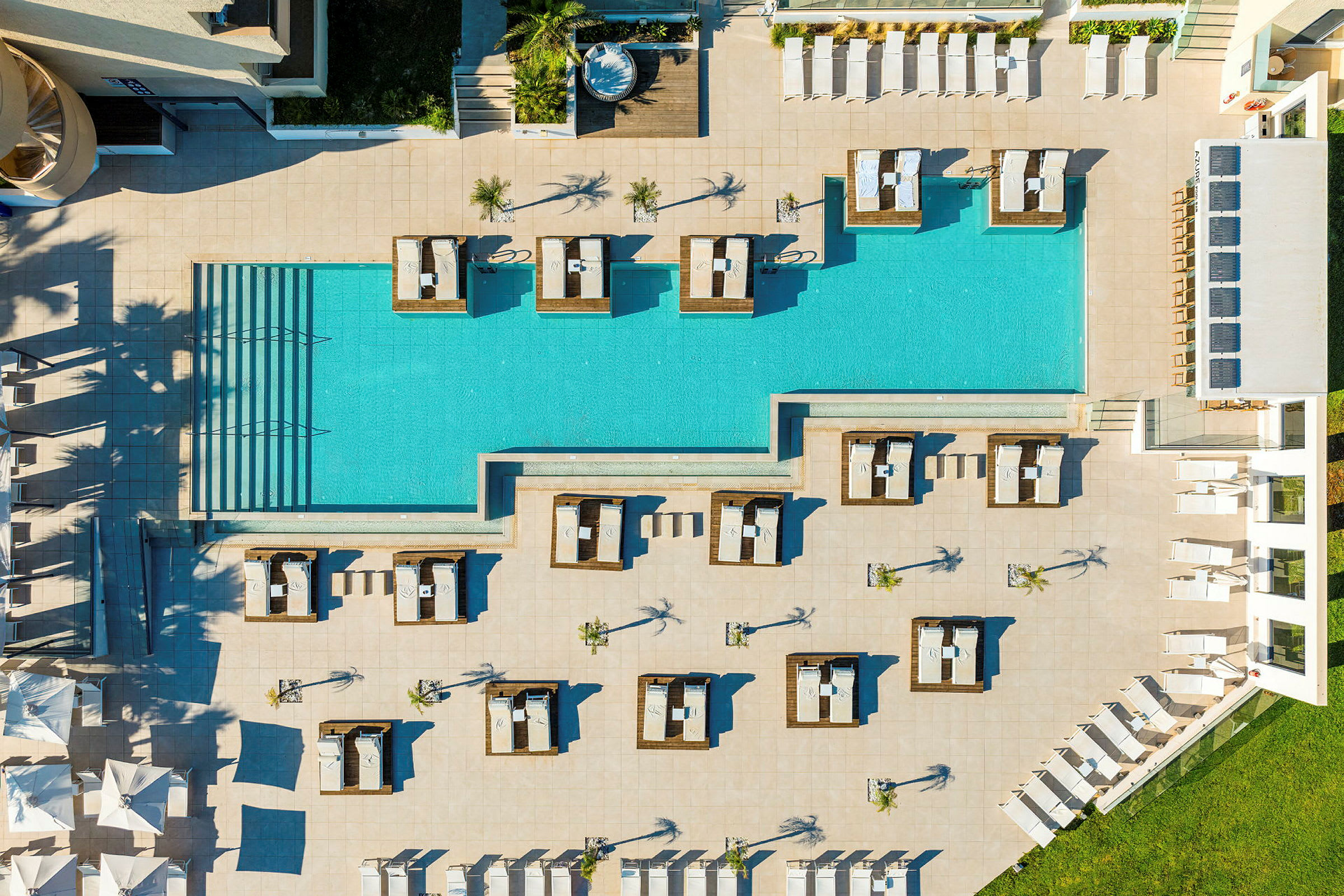Fugleperspektiv af et poolområde med liggestole og cabanas. (AI-genereret tekst)