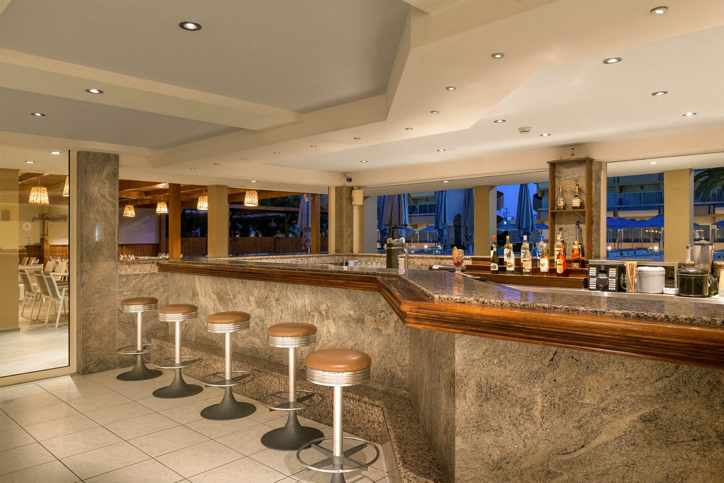 En hotelbar med flere siddepladser og en granitbordplade, synlige drinkflasker og stole. (AI-genereret tekst)