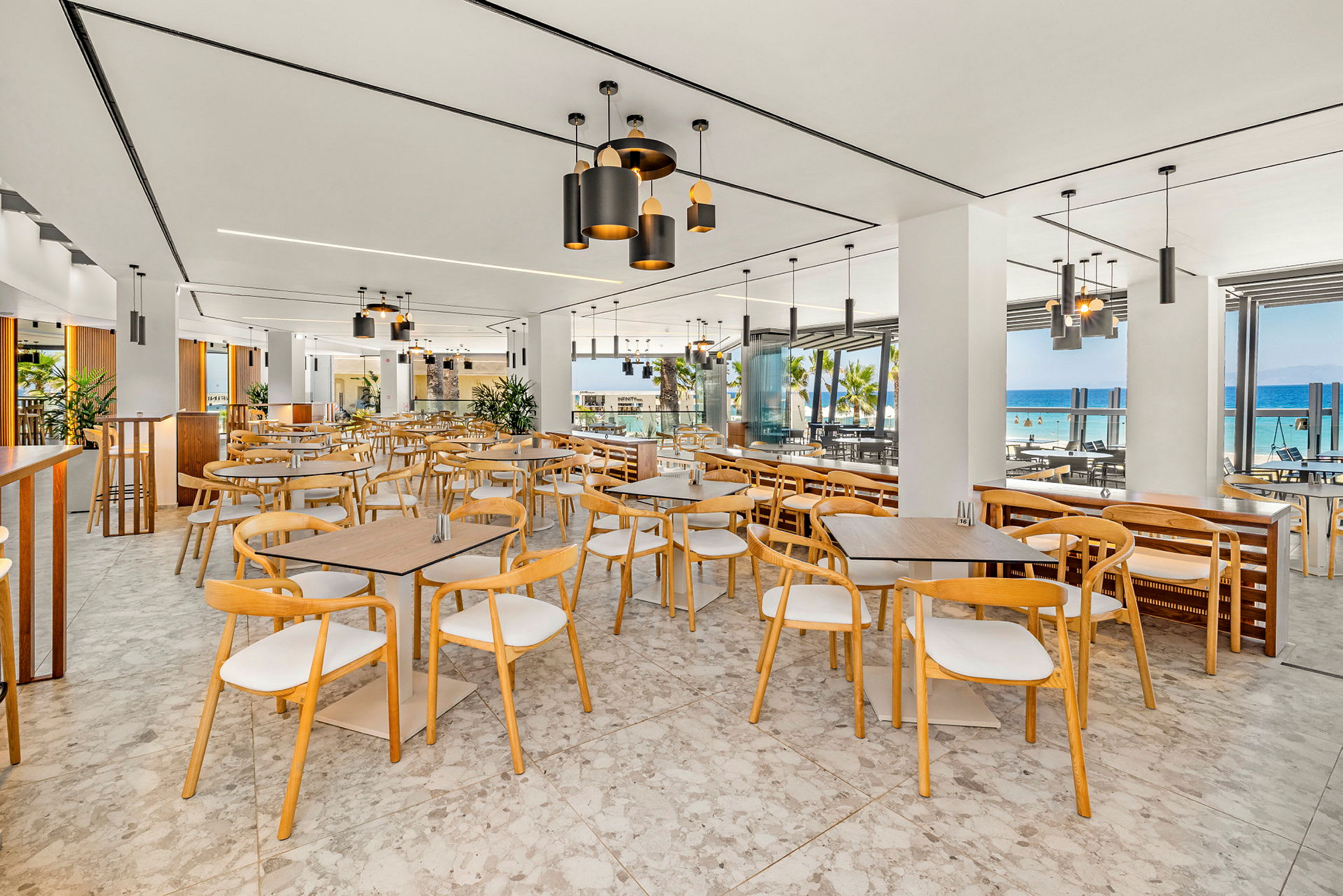 Restaurant med moderne møbler og store vinduer med udsigt over havet. (AI-genereret tekst)