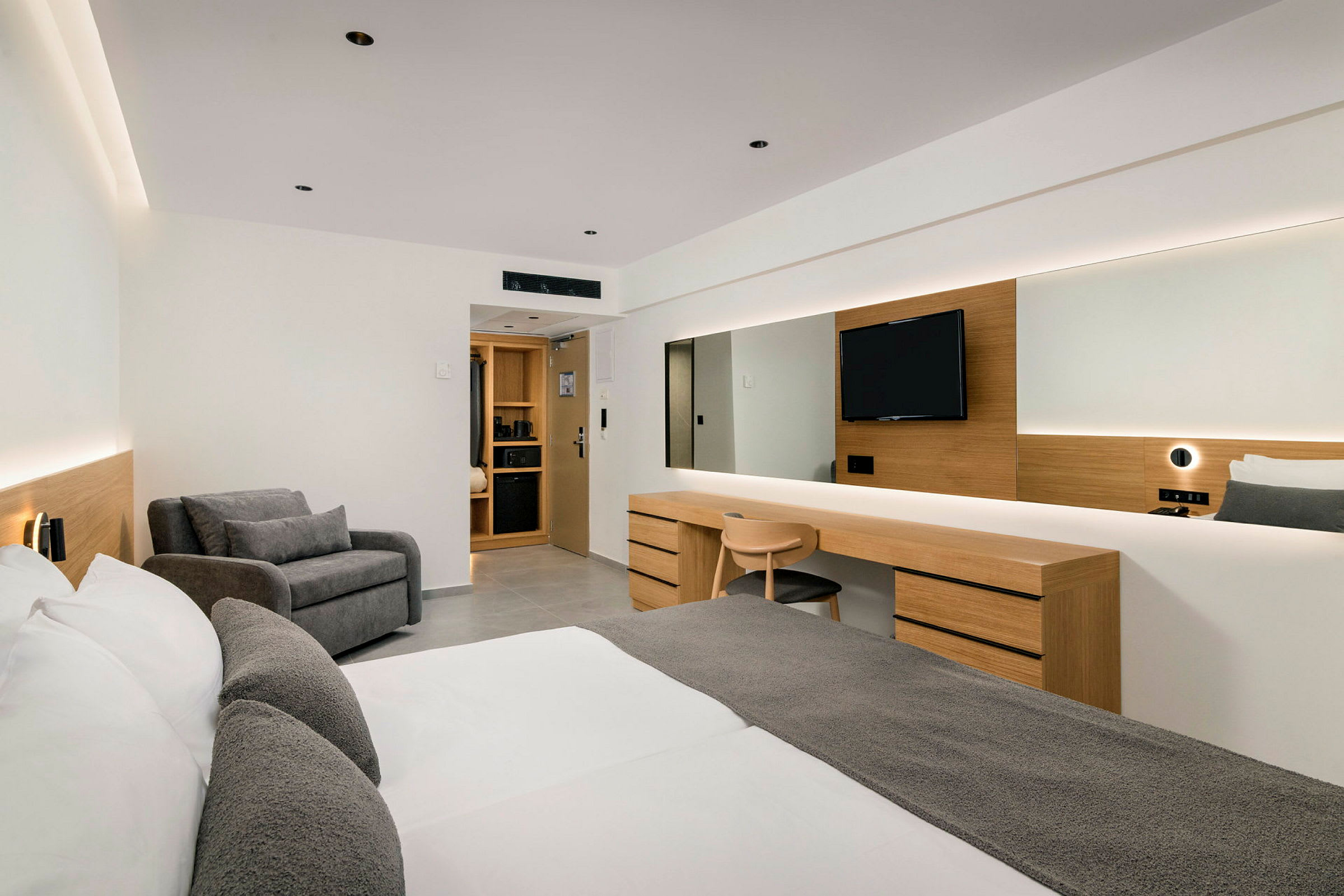 Et moderne hotelværelse med dobbeltseng, skrivebord, siddeområde og TV. (AI-genereret tekst)