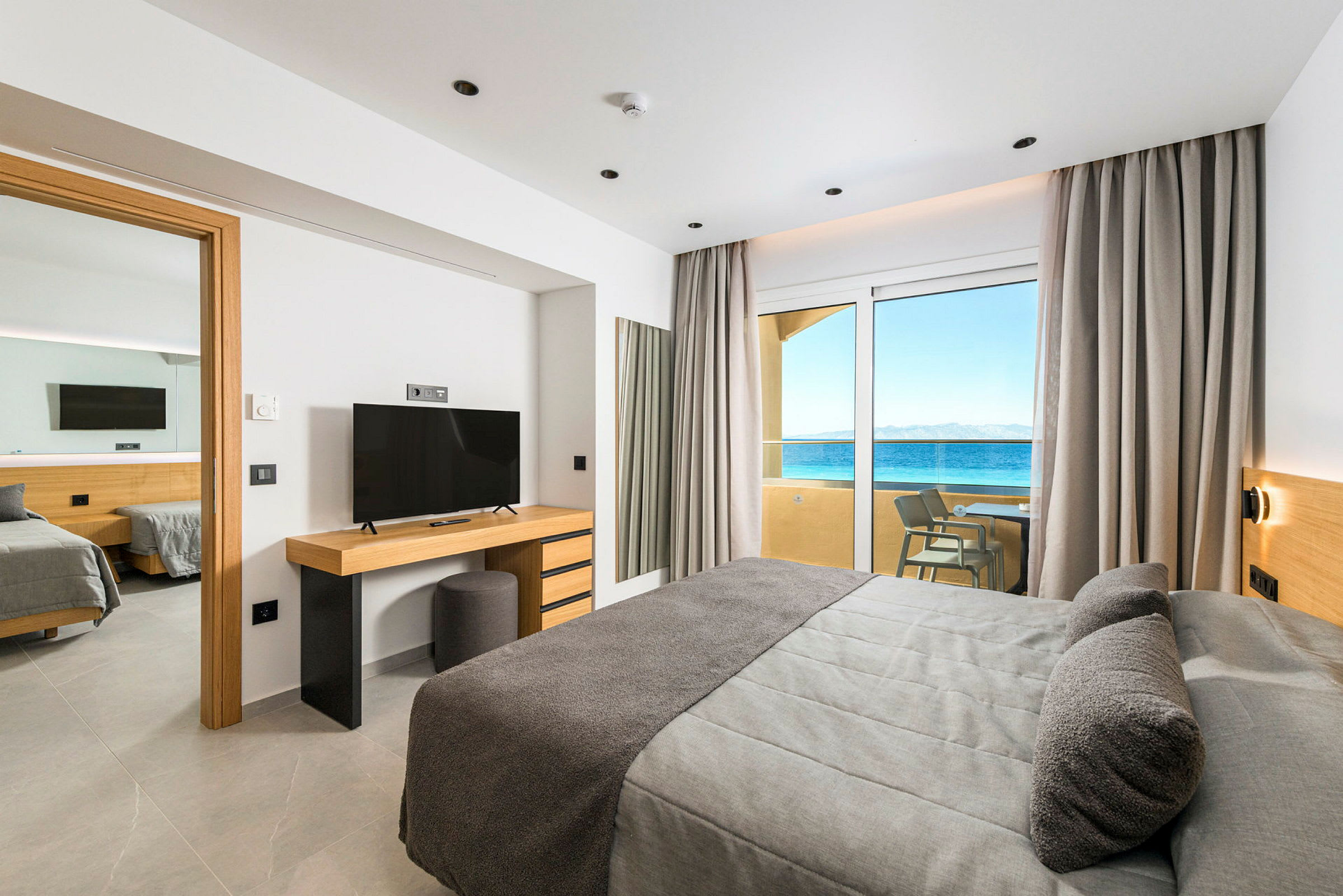 Hotelværelse med moderne indretning, havudsigt gennem glasdøre og adgang til altan. (AI-genereret tekst)