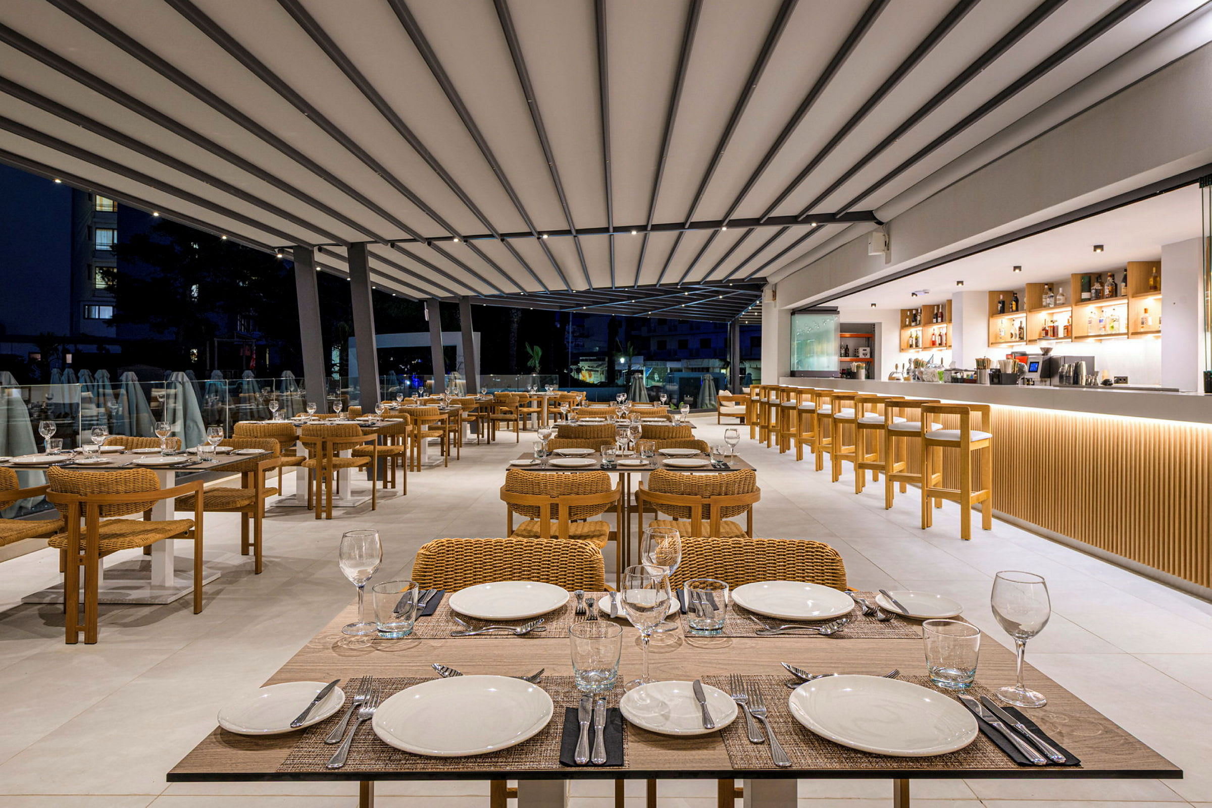 En moderne restaurant med dækkede borde og stole i flet samt en lang bardisk i baggrunden. (AI-genereret tekst)