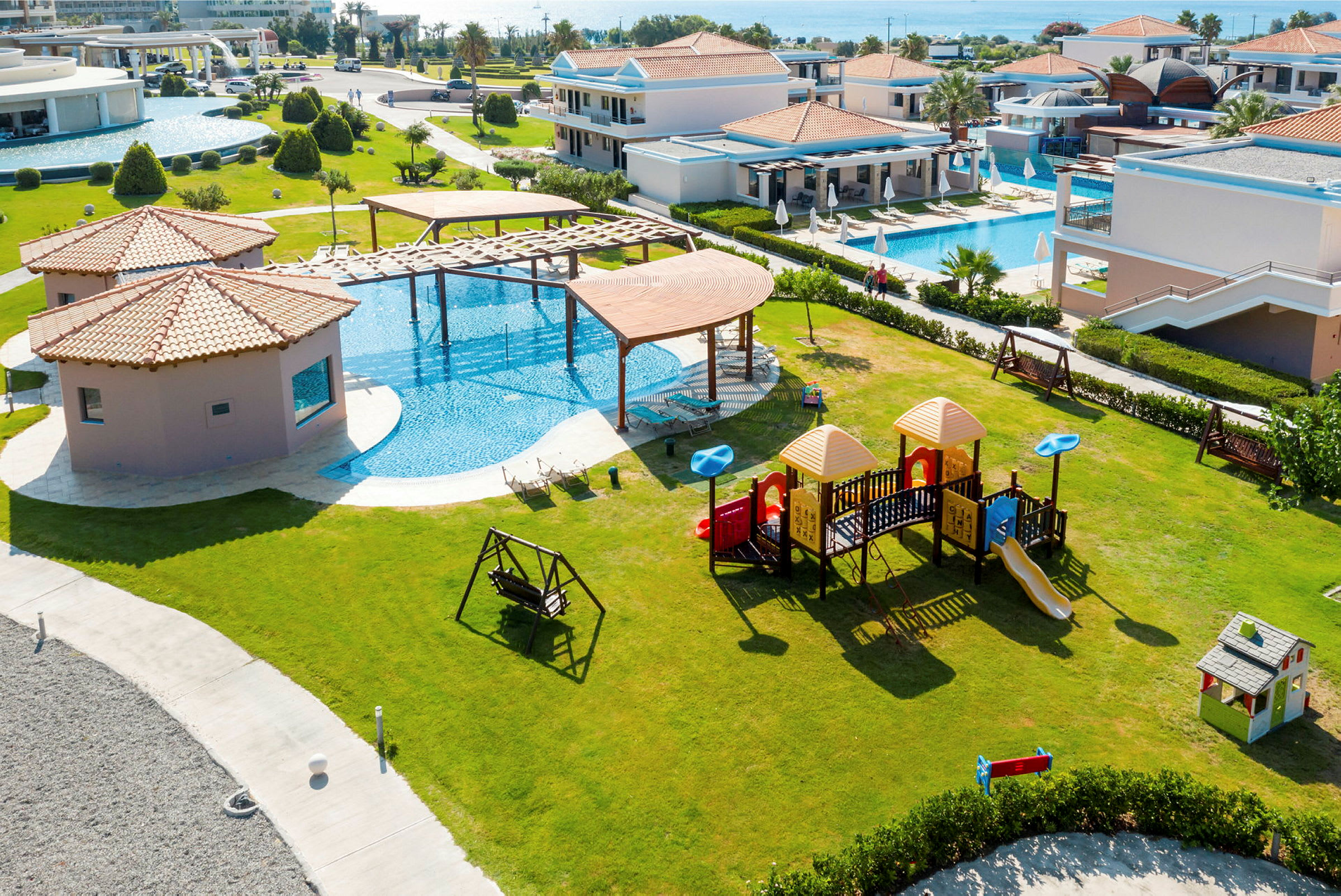 Hotelområde med legeplads og swimmingpools. (AI-genereret tekst)