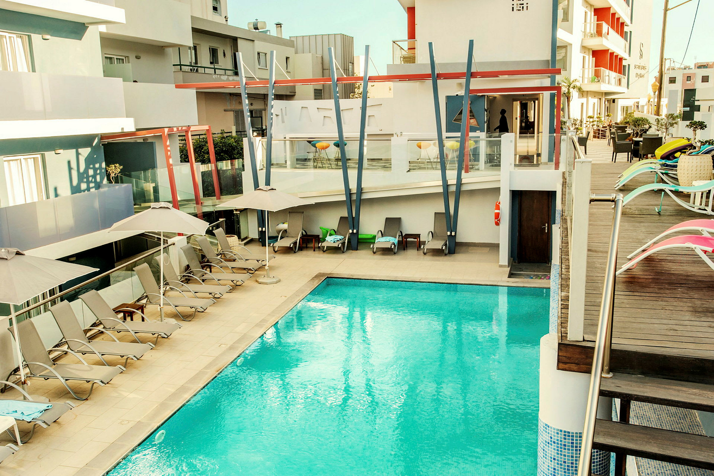 Udendørs pool ved et moderne hotel med liggestole og parasoller. (AI-genereret tekst)