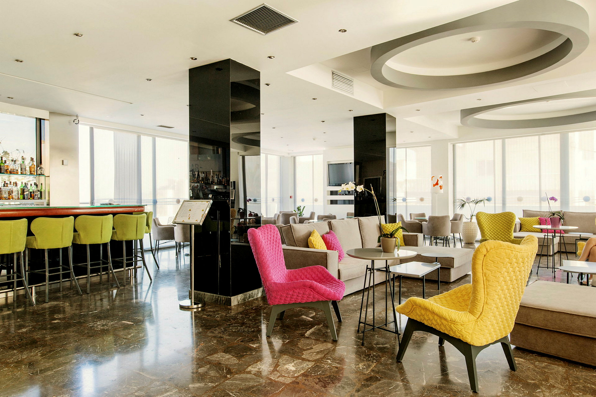 Interiøret i en moderne hotellobby med farverige stole og siddegrupper. (AI-genereret tekst)