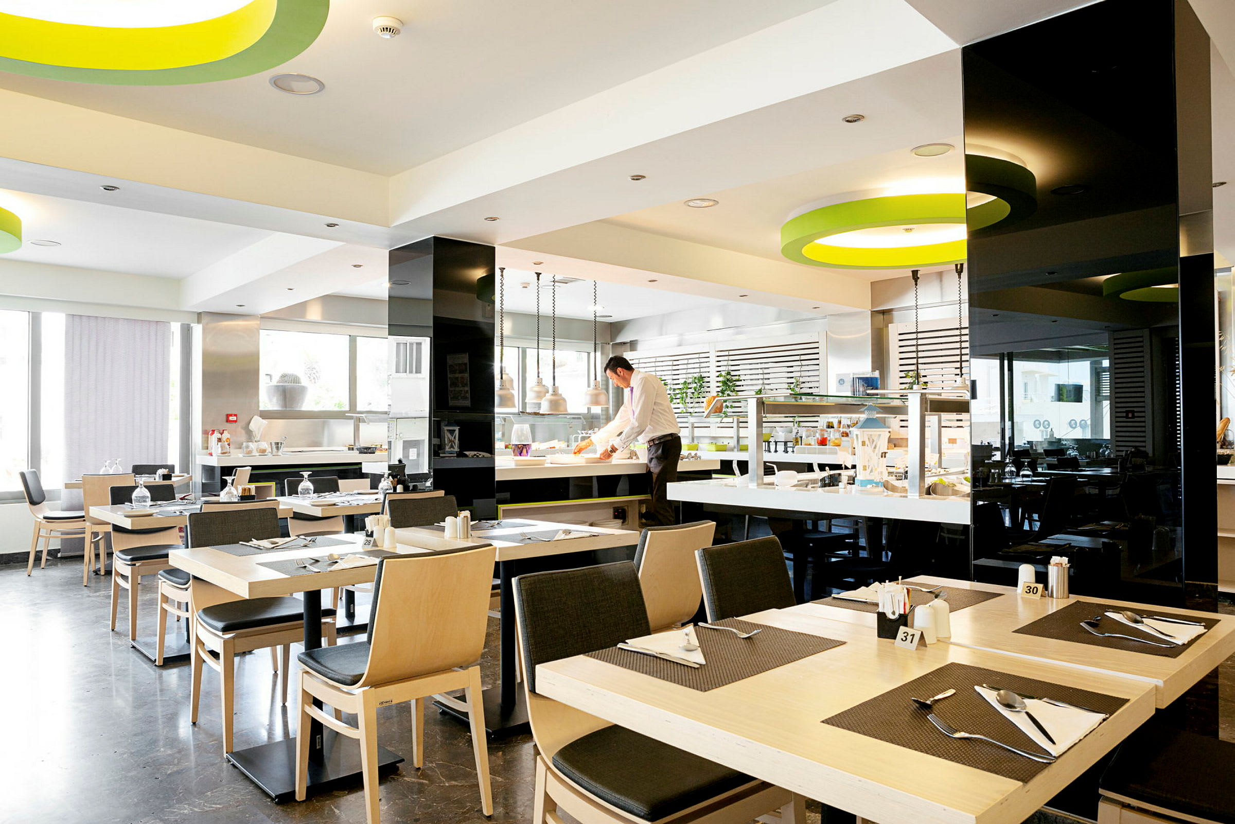 Moderne og lyse restaurantlokaler med dækkede borde og et serveringsområde. (AI-genereret tekst)