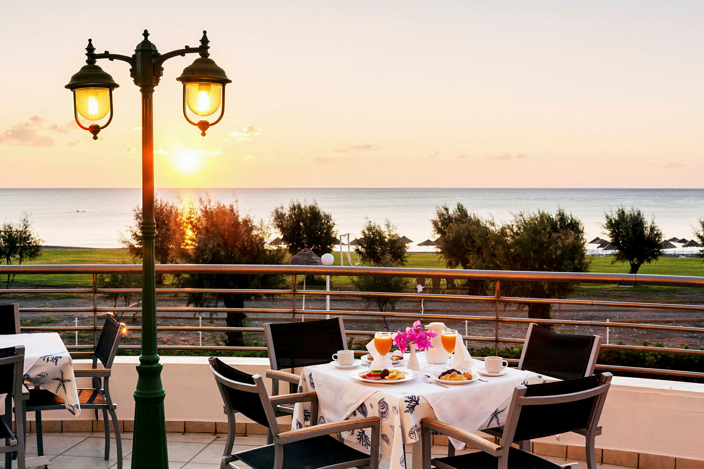 Udsigt over et bord med morgenmadsservering på en terrasse med havet i baggrunden. (AI-genereret tekst)