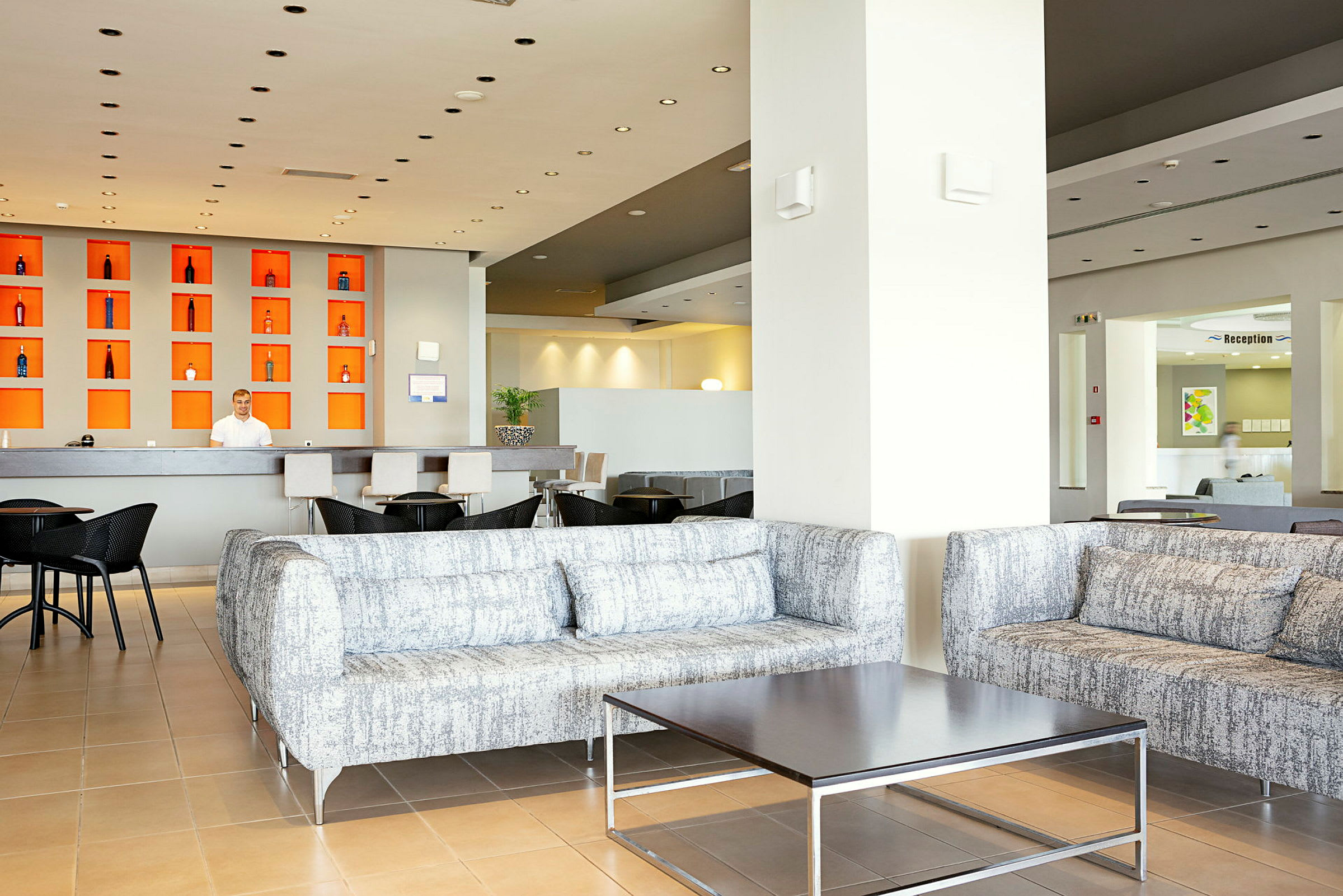 Lys hotel lobbyområde med sofa-grupper og reception desk. (AI-genereret tekst)