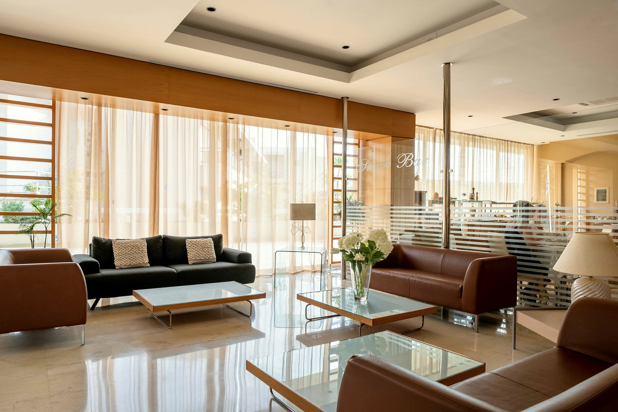 Hotellets lobby med sofaer og glasborde. (AI-genereret tekst)
