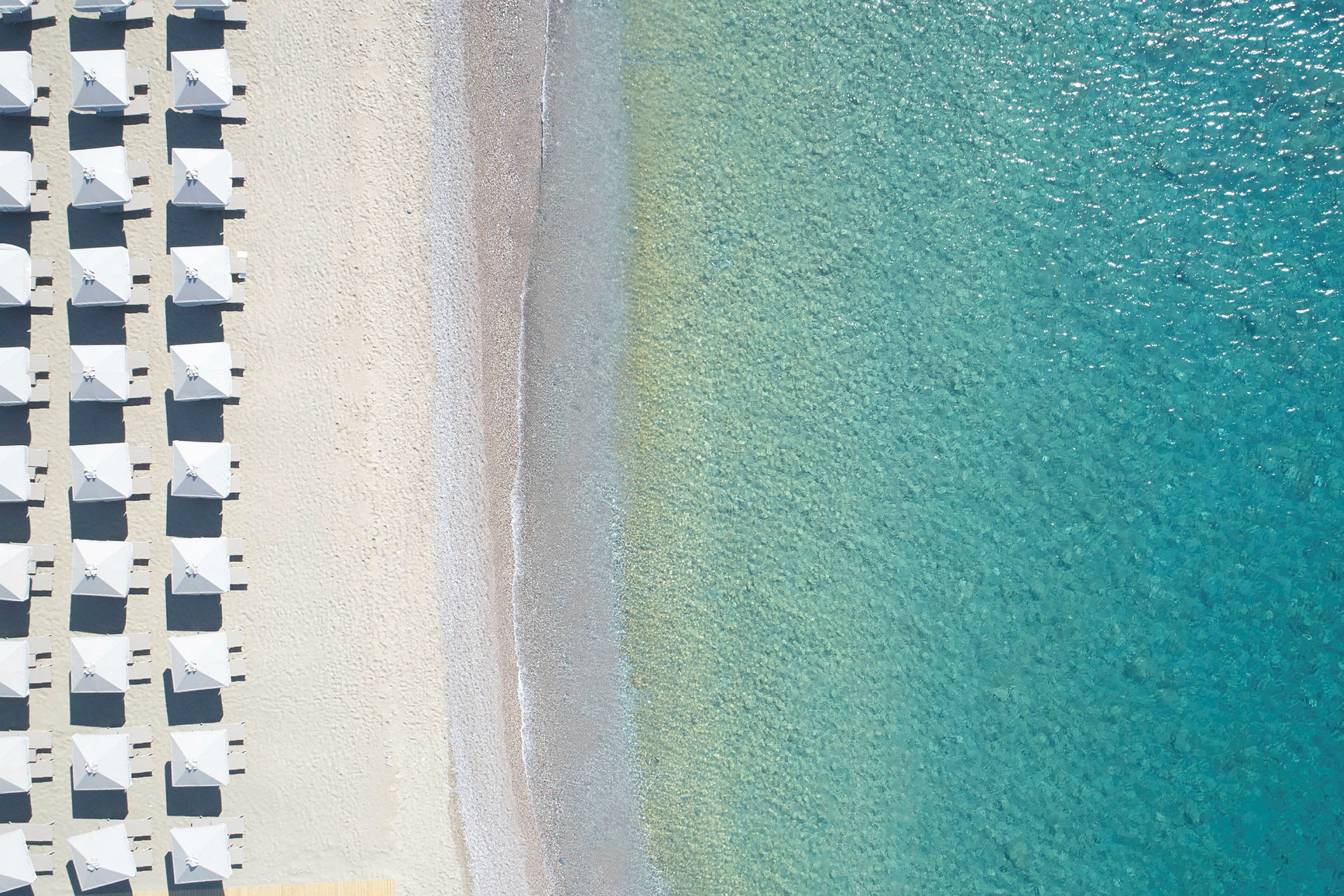 Luftfoto af strand med parasoller og klart turkis vand. (AI-genereret tekst)