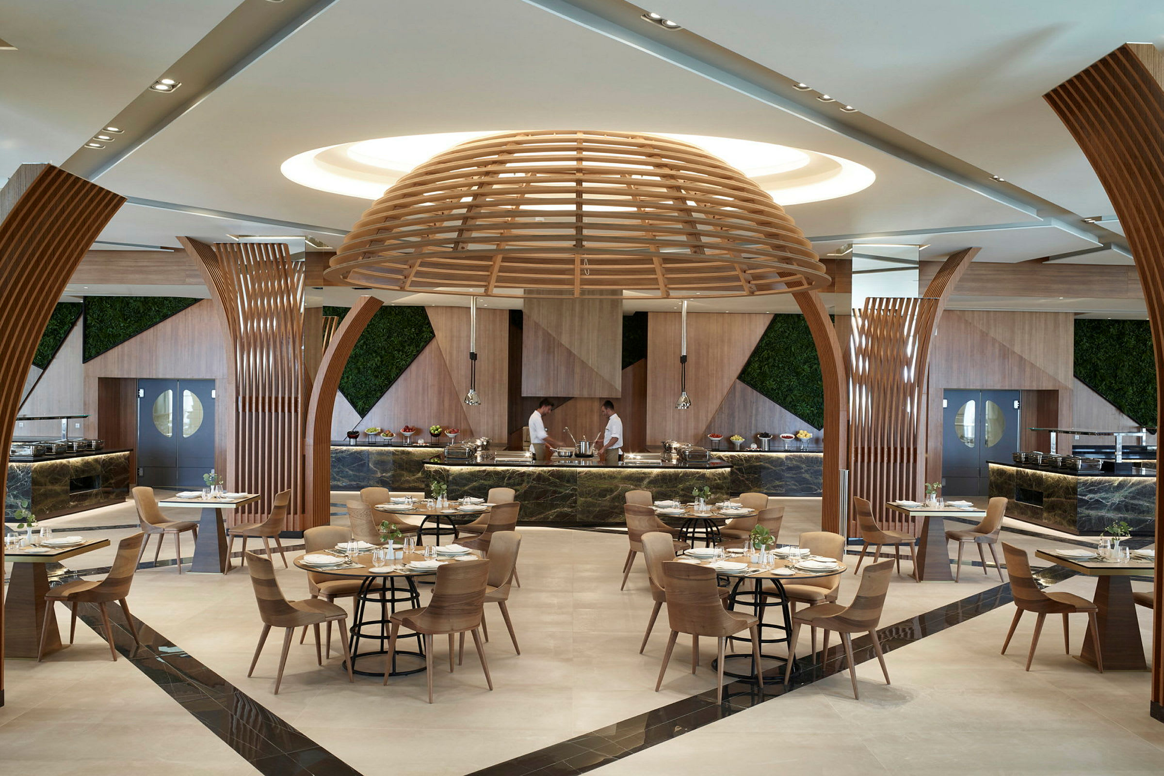 Et moderne restaurantinteriør med træ detaljer og to kokke bag serveringsdisken. (AI-genereret tekst)
