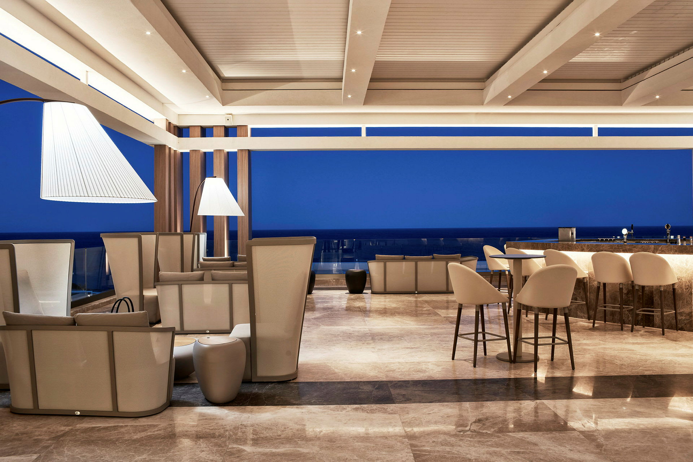 En moderne lounge med siddepladser og en bardisk, med blå himmel i baggrunden. (AI-genereret tekst)