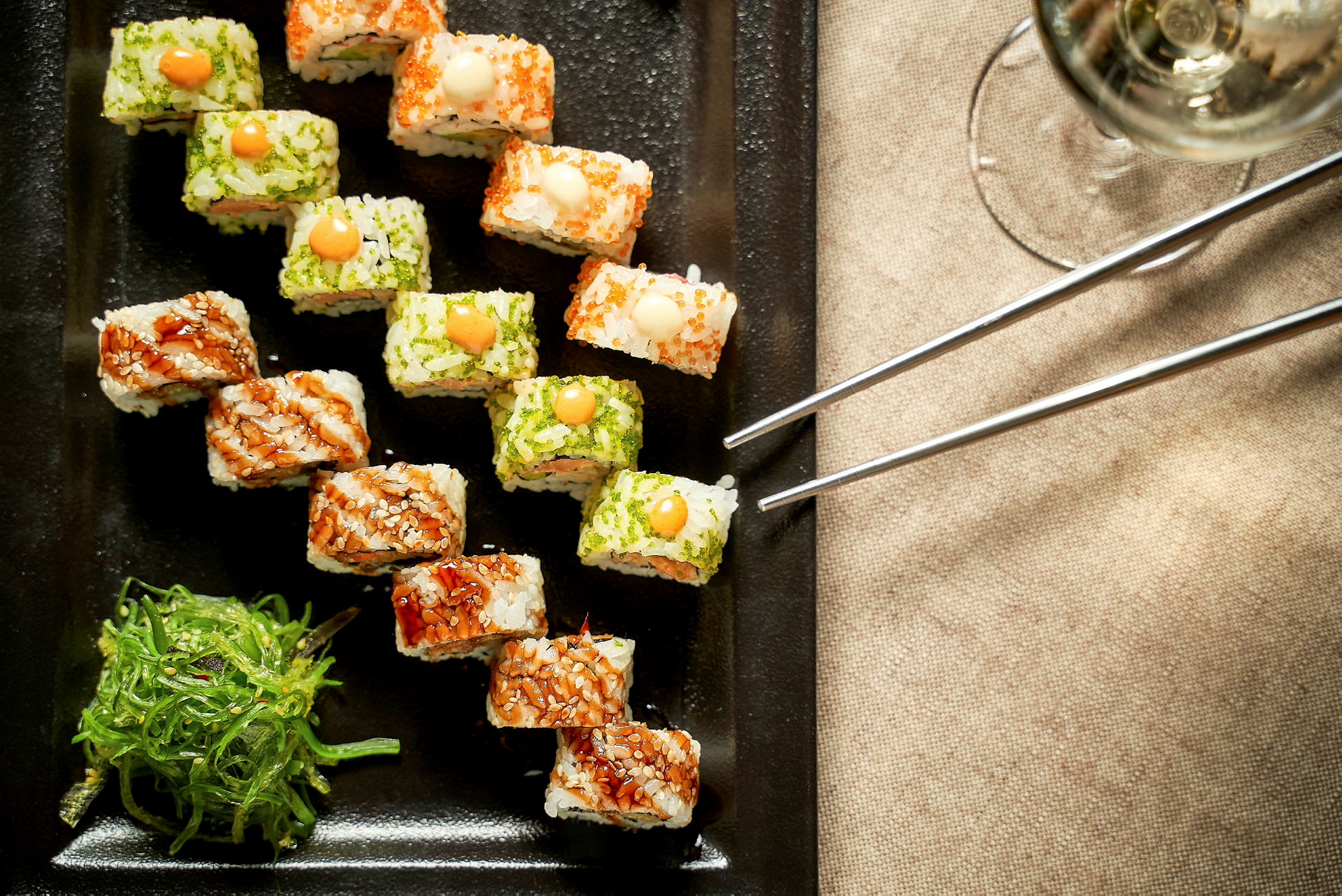 Sushi serveret på en sort tallerken med tangsalat ved siden af. (AI-genereret tekst)
