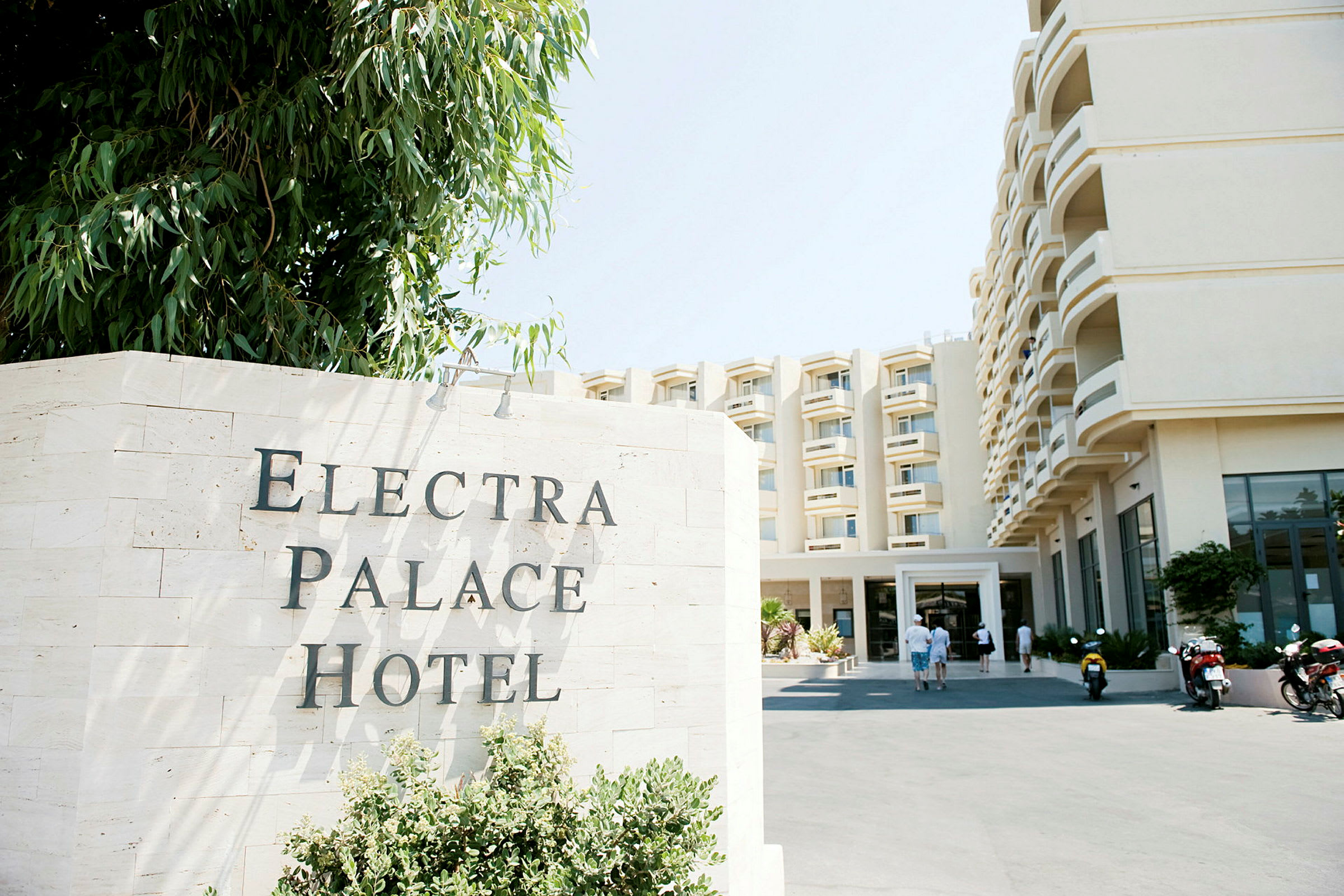 Hotellets facade med skiltet 'Electra Palace Hotel' foran. (AI-genereret tekst)