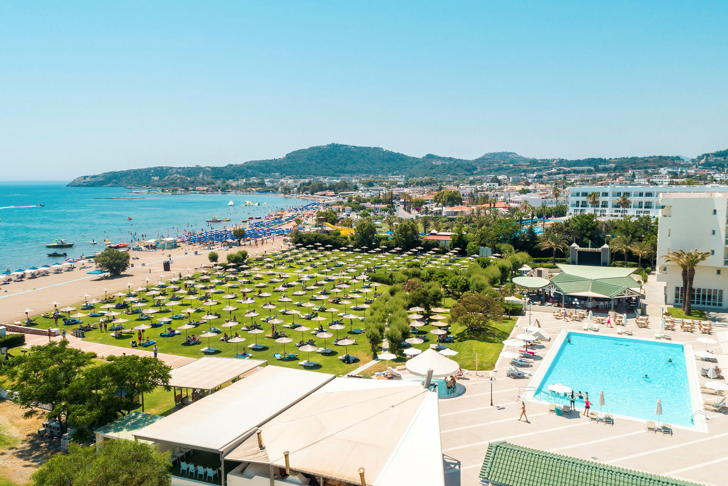 Poolområde foran hotel med udsigt over stranden og havet. (AI-genereret tekst)
