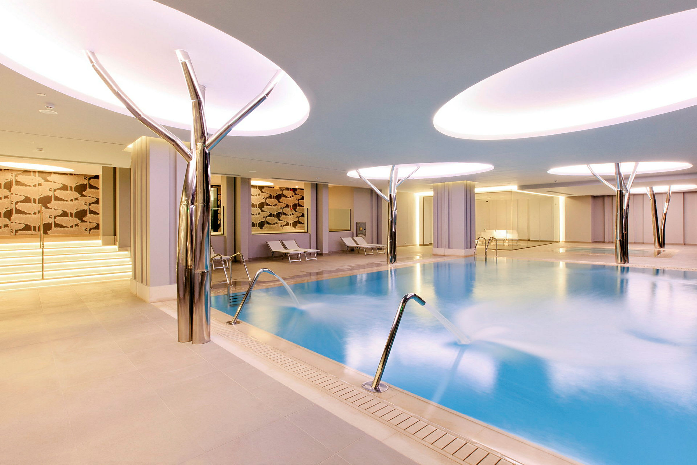 Billede af et moderne indendørs spa med pool og liggestole. (AI-genereret tekst)
