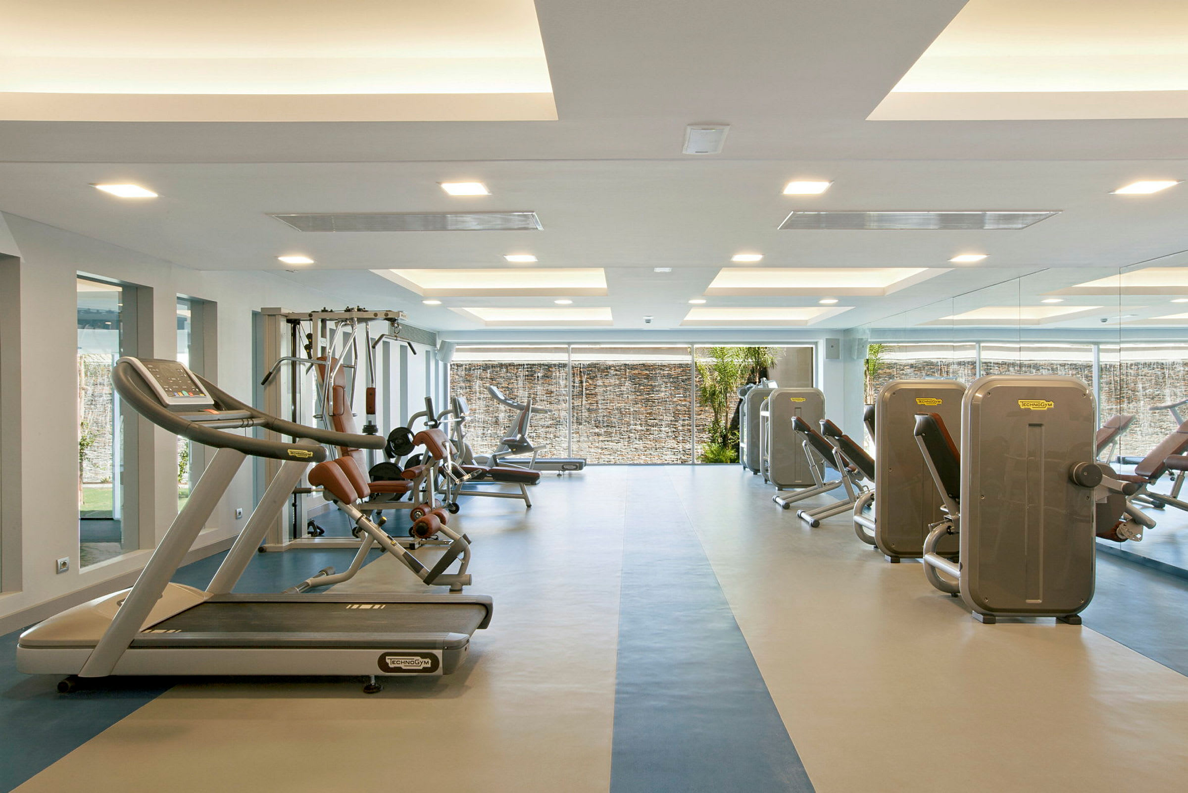Et fitnesscenter med forskellige træningsmaskiner og lyse indendørsområder. (AI-genereret tekst)