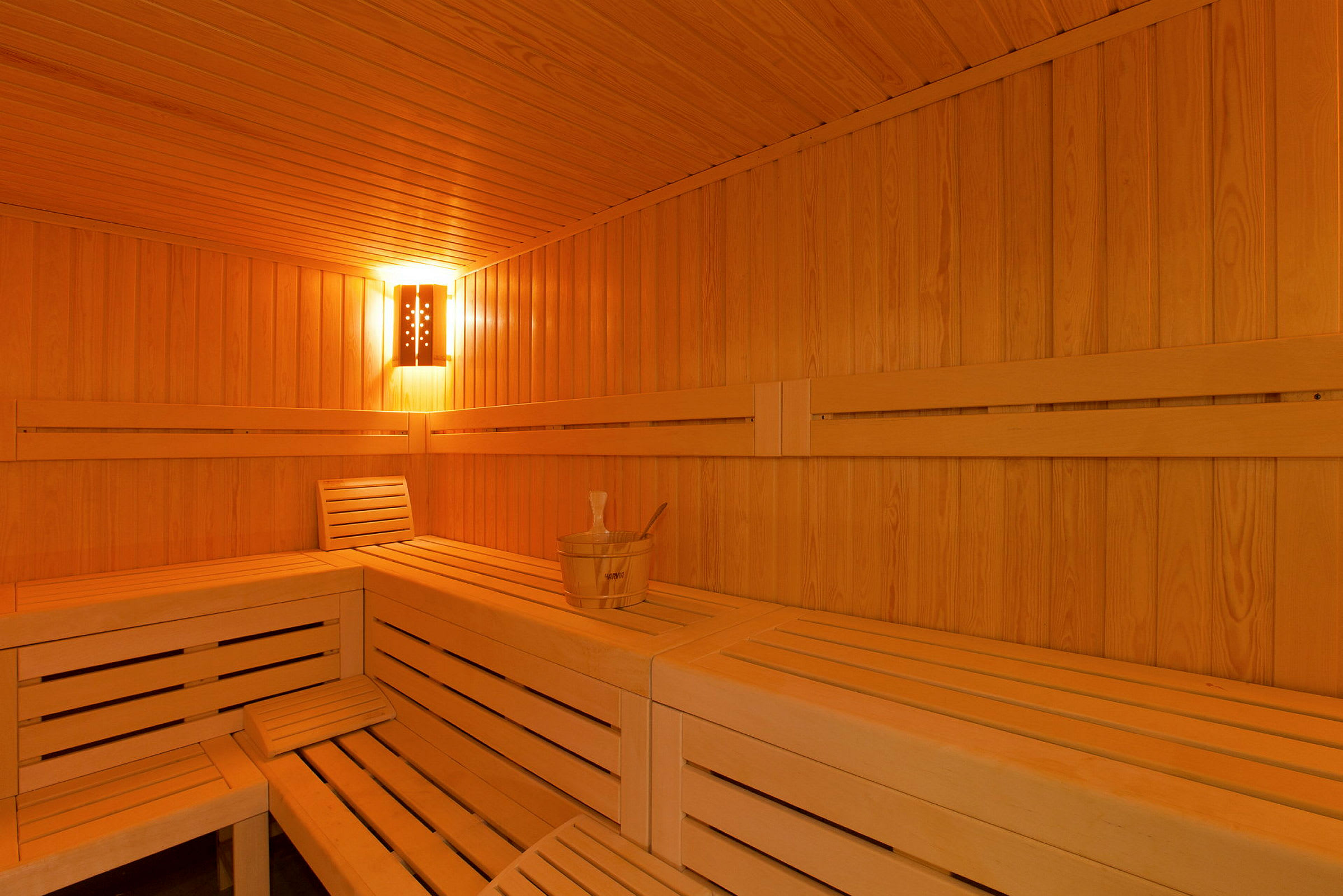 En trævenlig sauna med bænke og en vandspand. (AI-genereret tekst)
