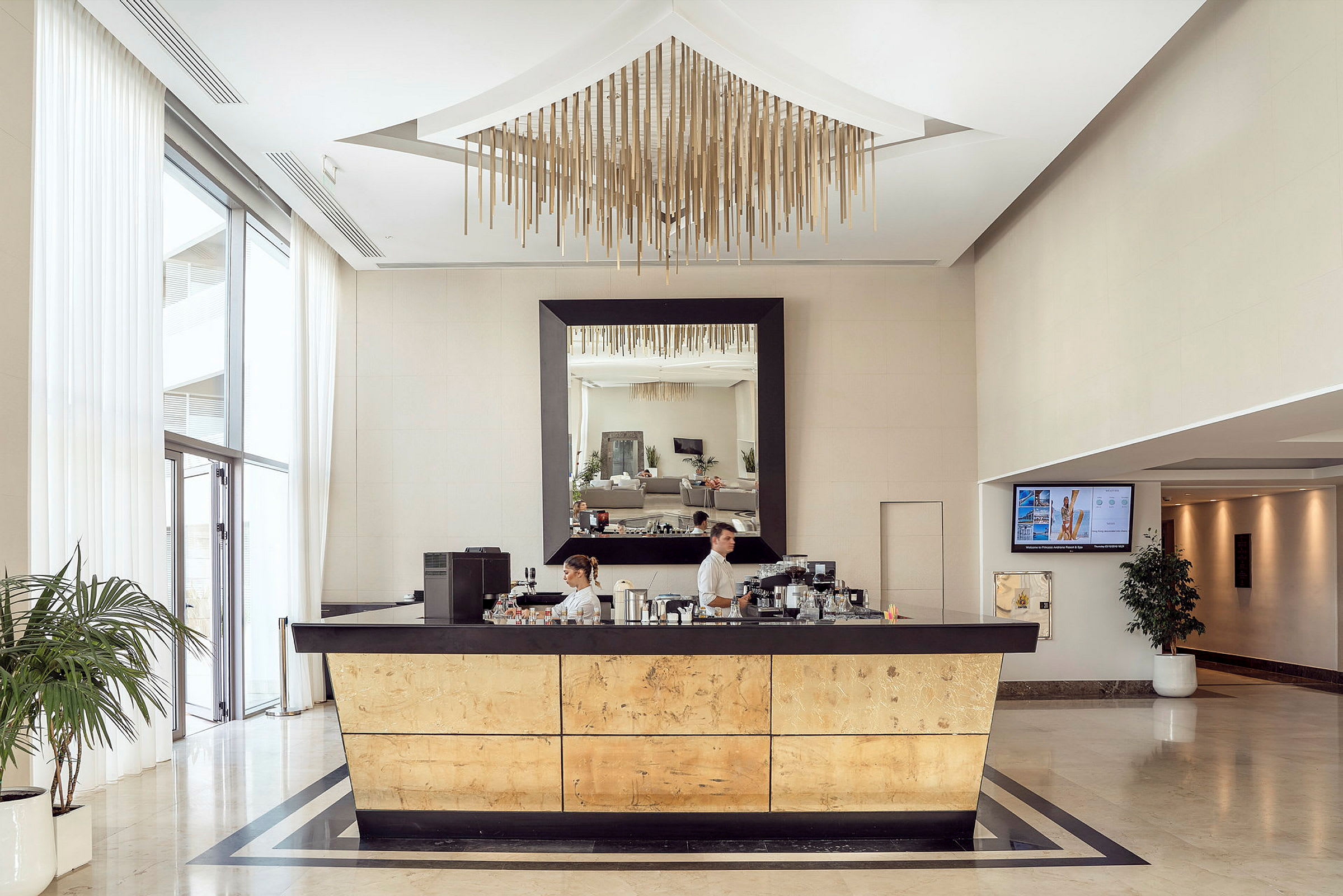 En lobby med en reception med gyldne detaljer og et spejl ovenover. (AI-genereret tekst)